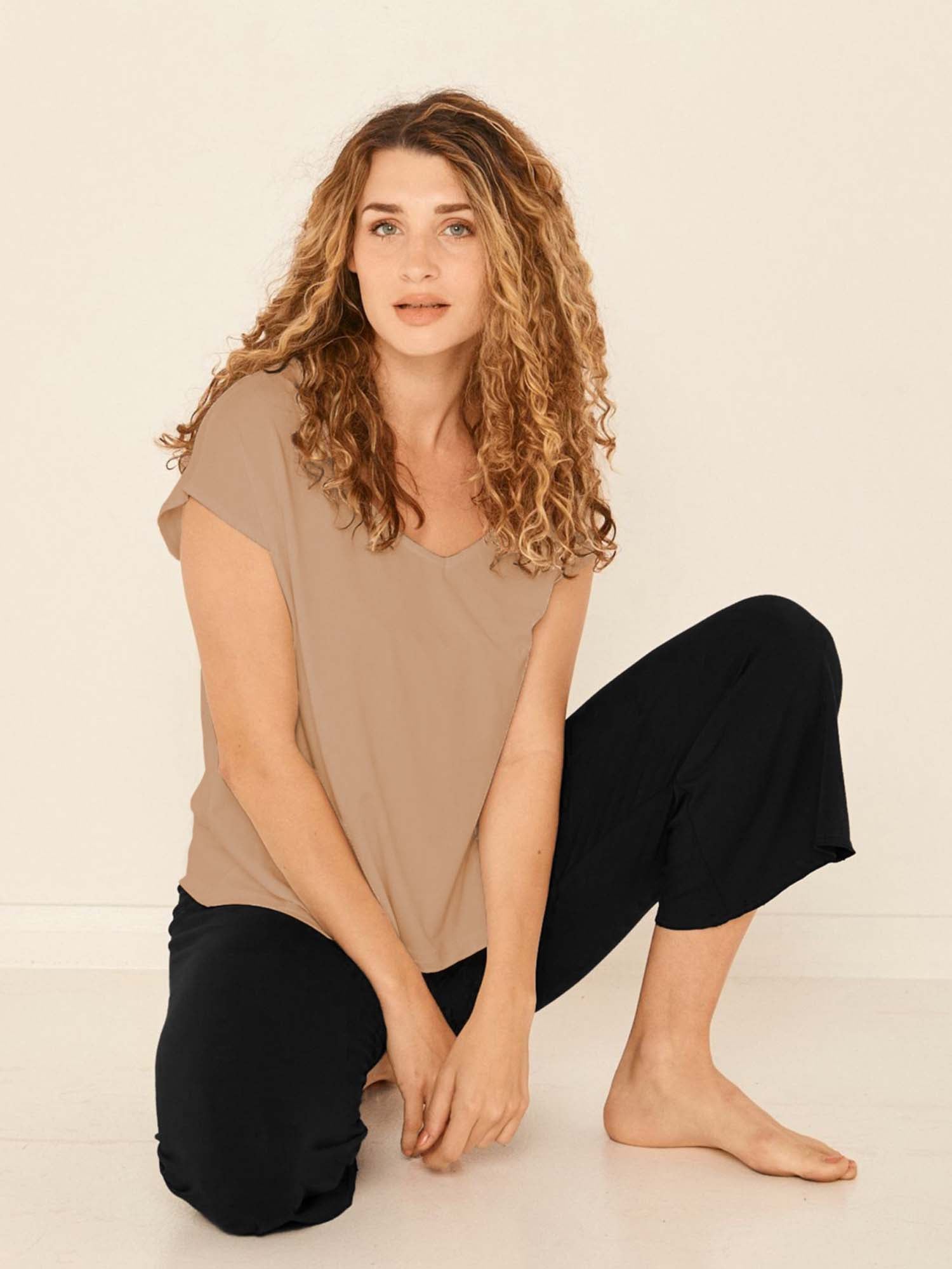 Model wearing a reversible caramel brown cap sleeved boxy style t-shirt with boat and v necklines, a loose oversized fit, women's bamboo clothing