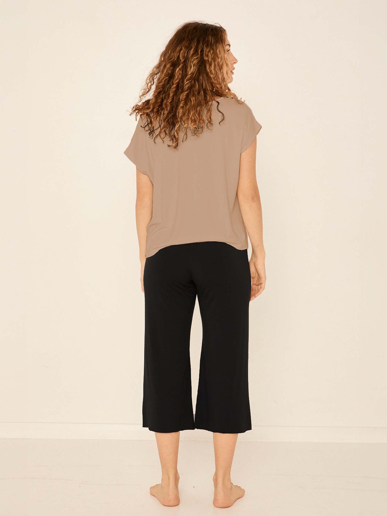 Model wearing a reversible caramel brown cap sleeved boxy style t-shirt with boat and v necklines, a loose oversized fit, women's bamboo clothing