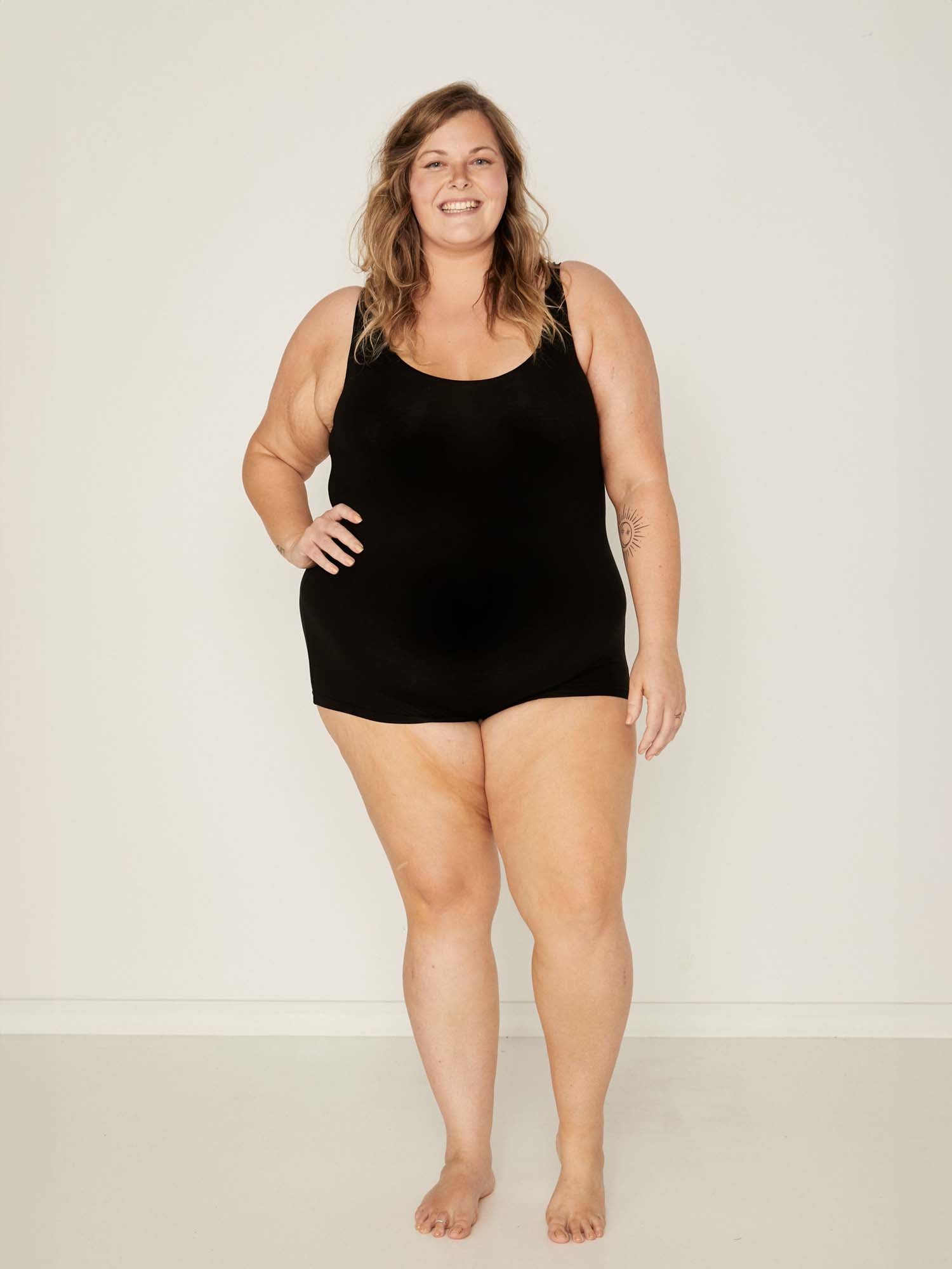 Model wearing a reversible black boyleg bodysuit with scoop and boat necklines, women's bamboo clothing