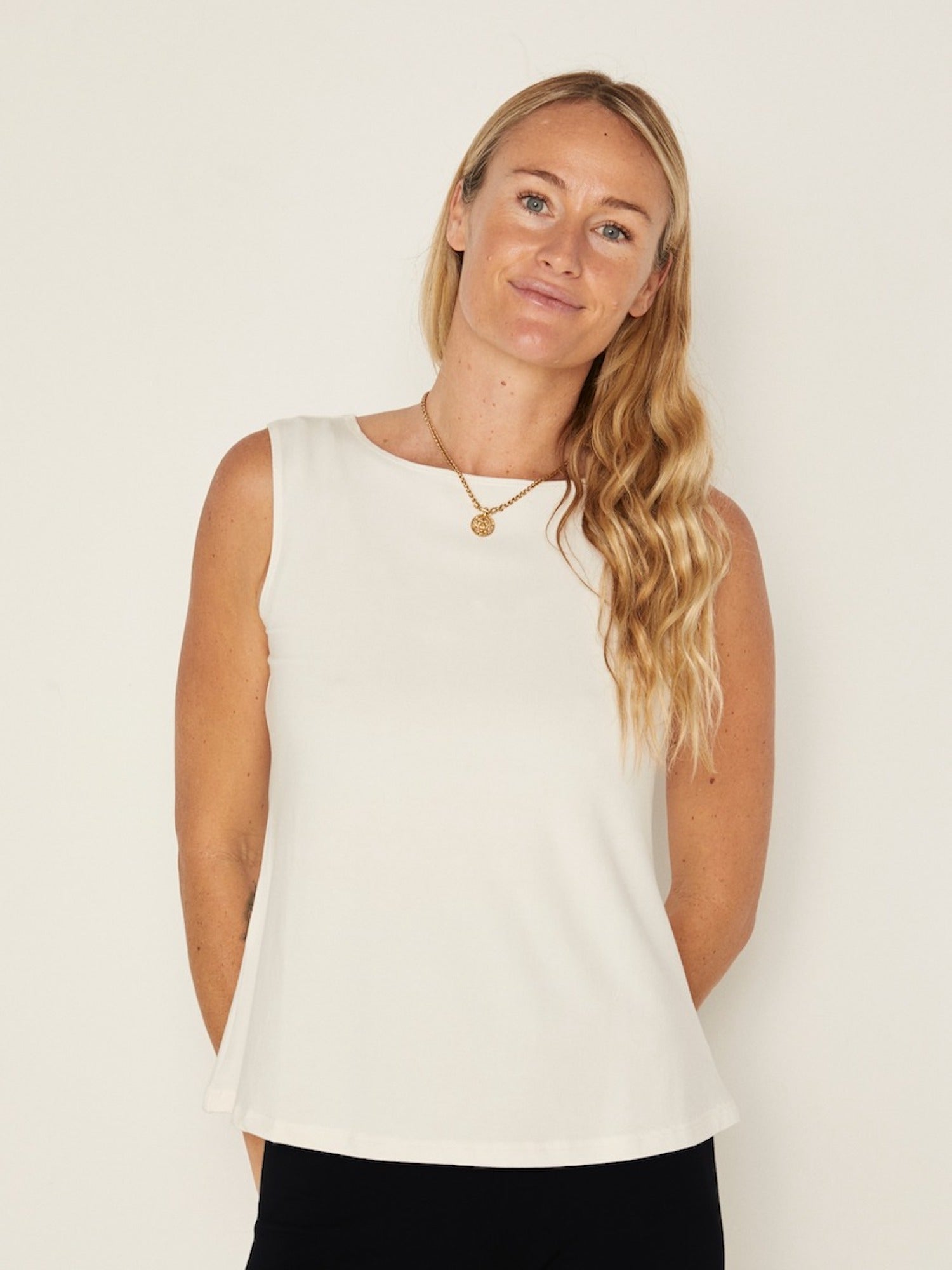 Model wearing a cream boat neck singlet with wide shoulder coverage, women's bamboo clothing