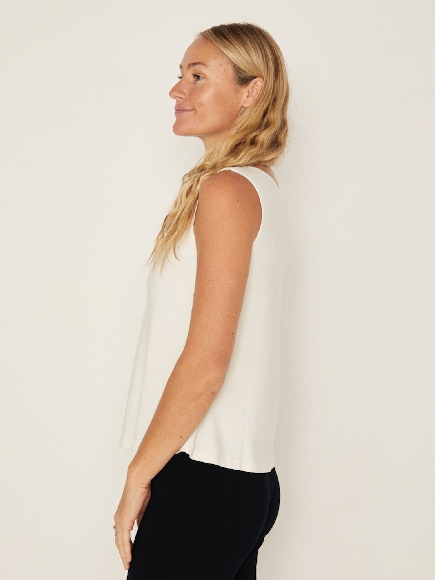 Model wearing a cream boat neck singlet with wide shoulder coverage, women's bamboo clothing