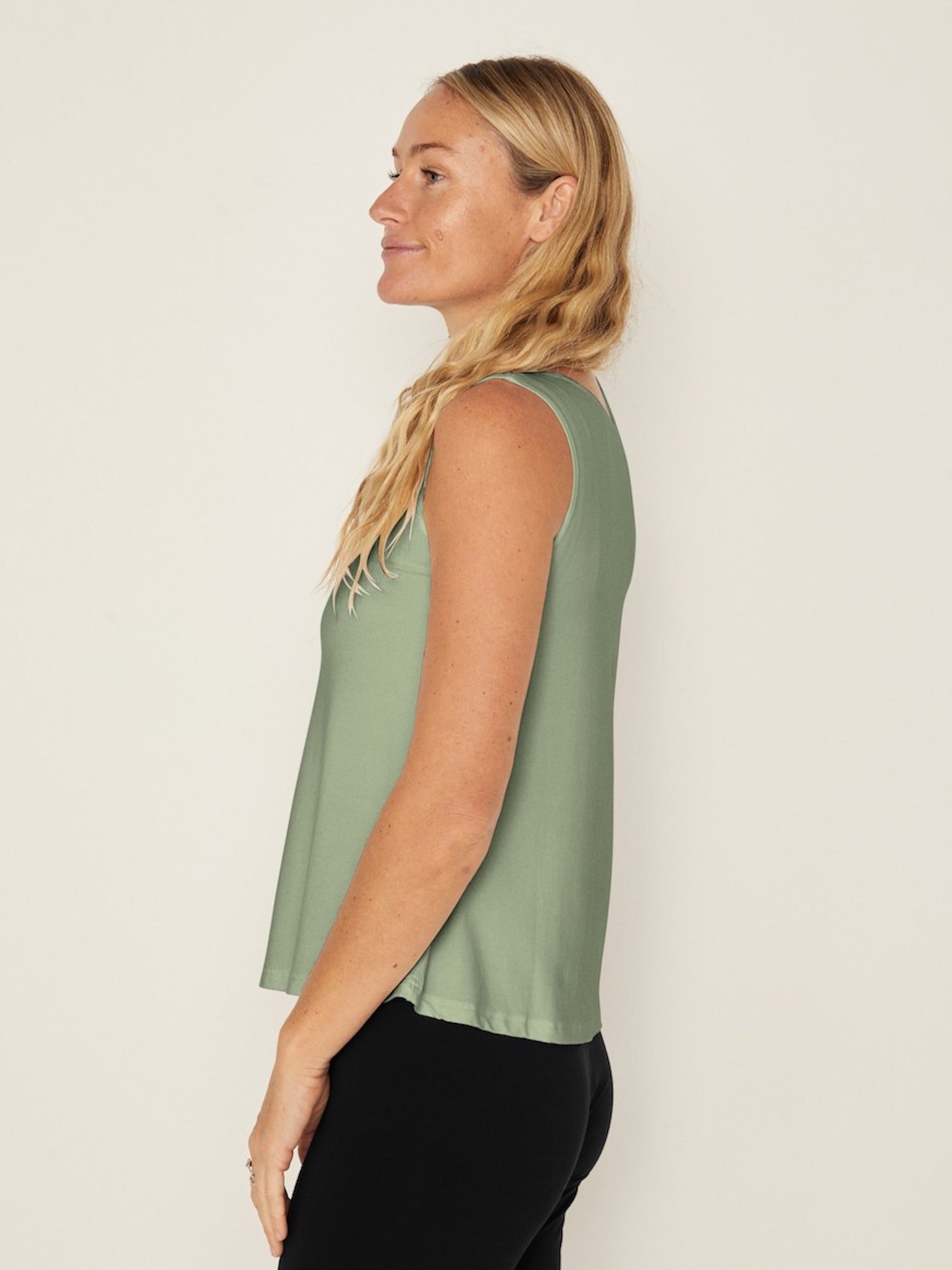 Model wearing a eucalyptus green boat neck singlet with wide shoulder coverage, women's bamboo clothing