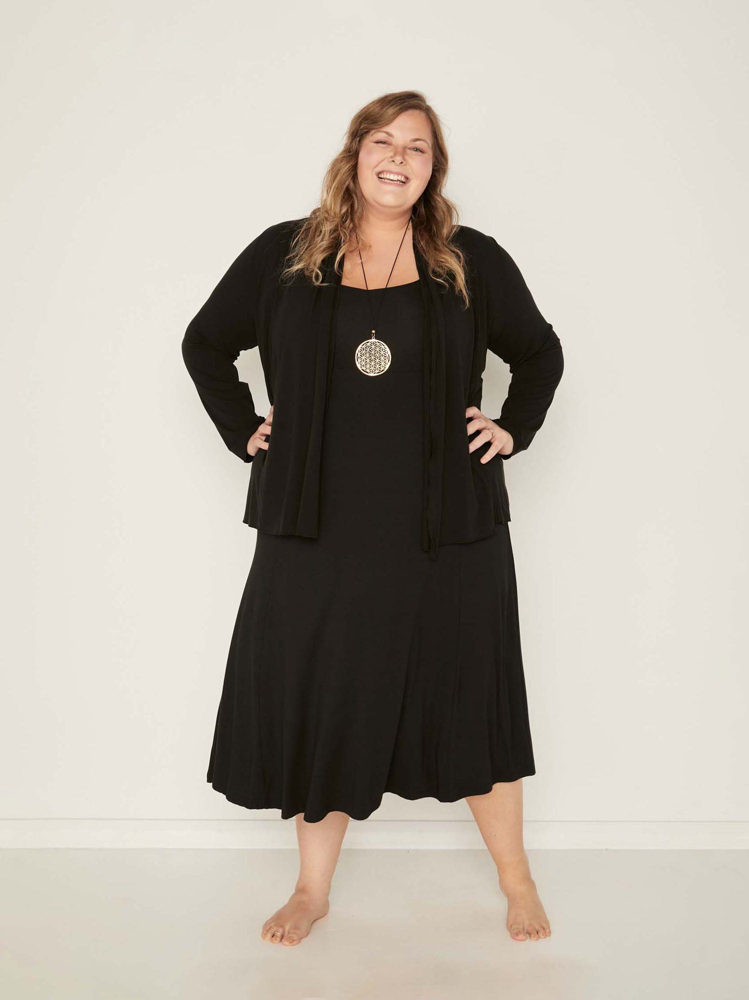 Model wearing a black mid length, sweetheart neckline swing style dress with black mid cardigan, women's bamboo clothing