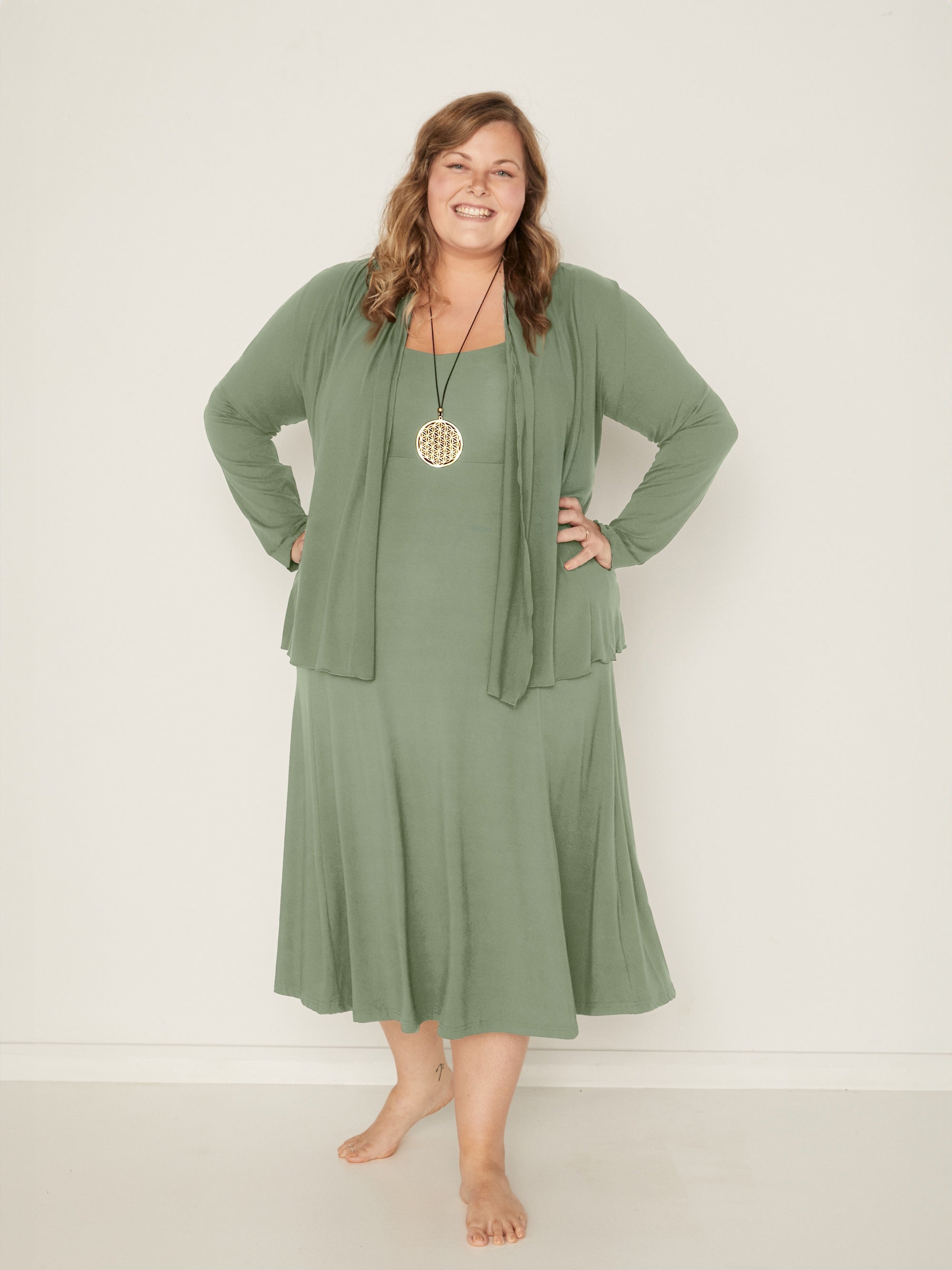 Model wearing a eucalyptus green mid length swing style dress with a sweetheart neckline and pockets, women's bamboo clothing