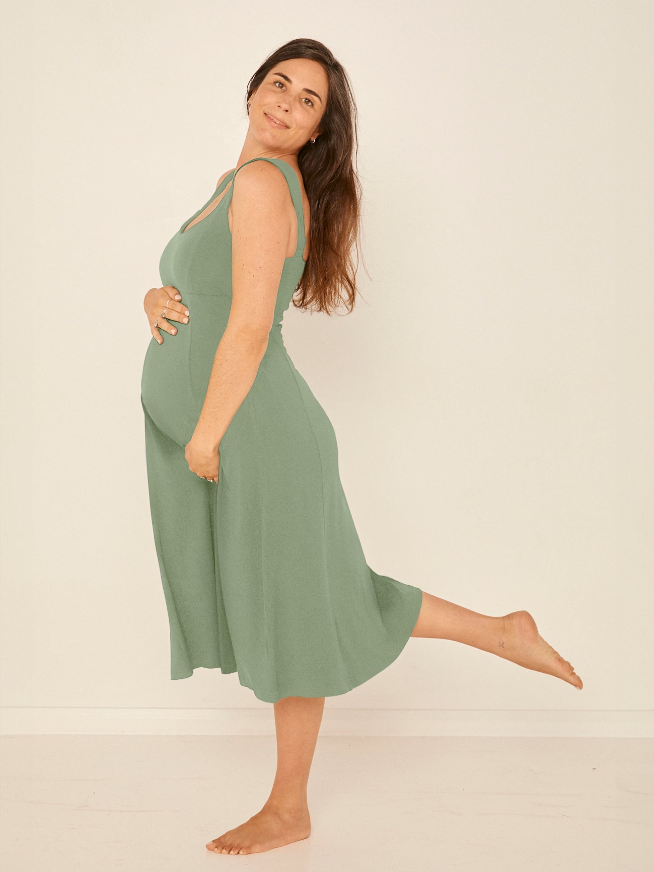 Model wearing a eucalyptus green mid length swing style dress with a sweetheart neckline and pockets, women's bamboo clothing