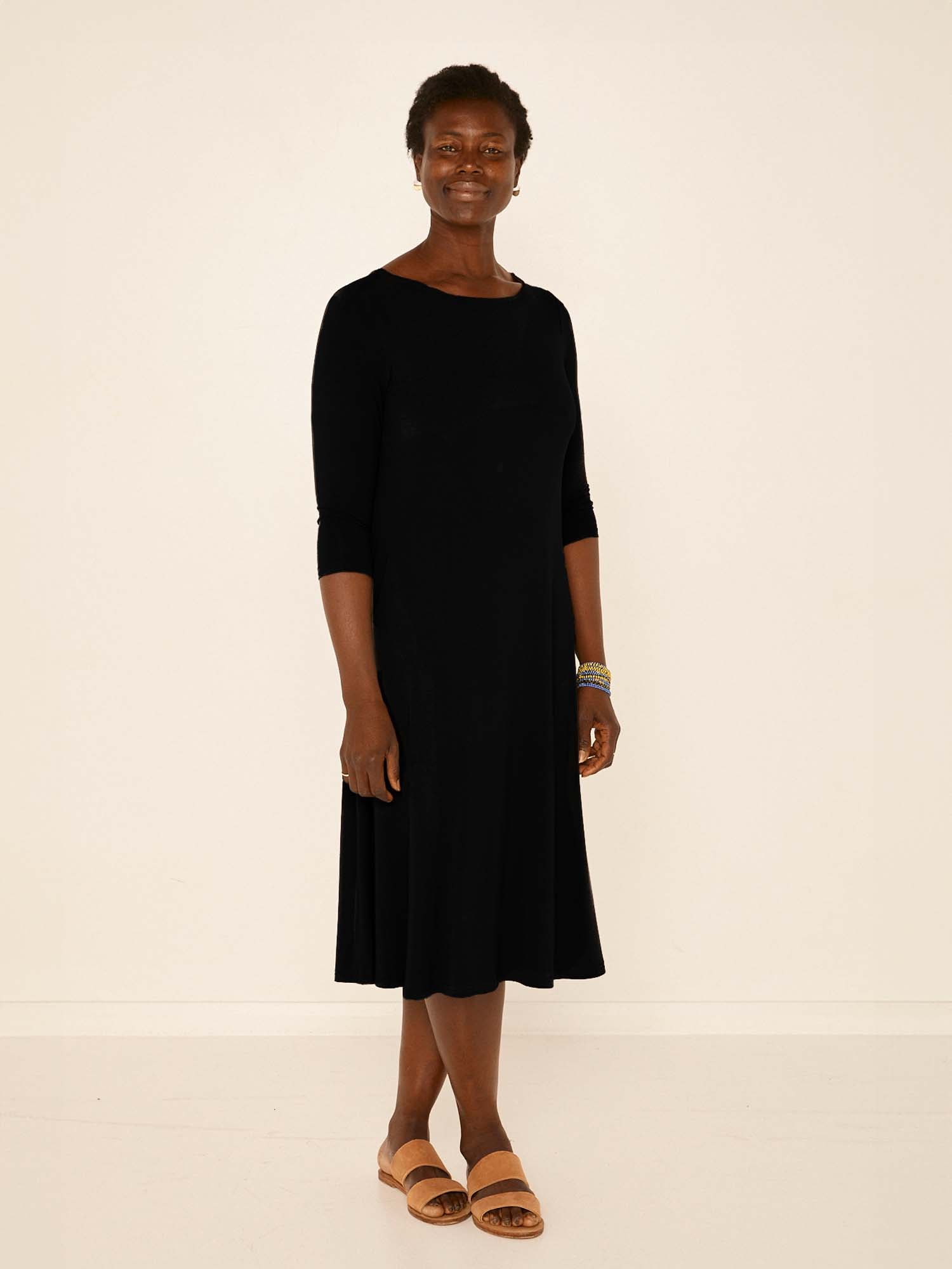 Model wearing a black mid sleeve 3/4 dress with a scoop neckline and generous swing in body, women's bamboo clothing