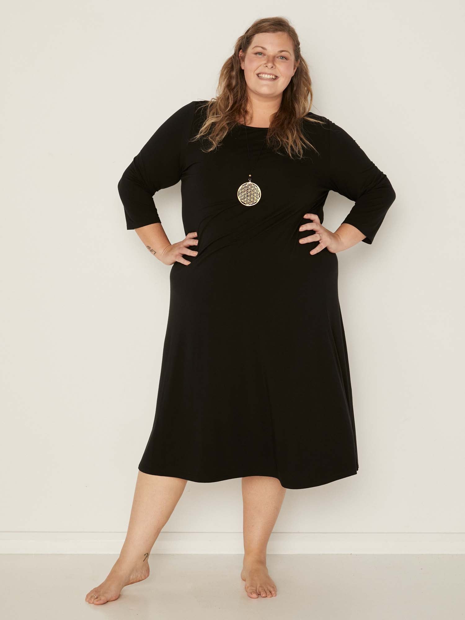 Model wearing a black mid sleeve 3/4 dress with a scoop neckline and generous swing in body, women's bamboo clothing