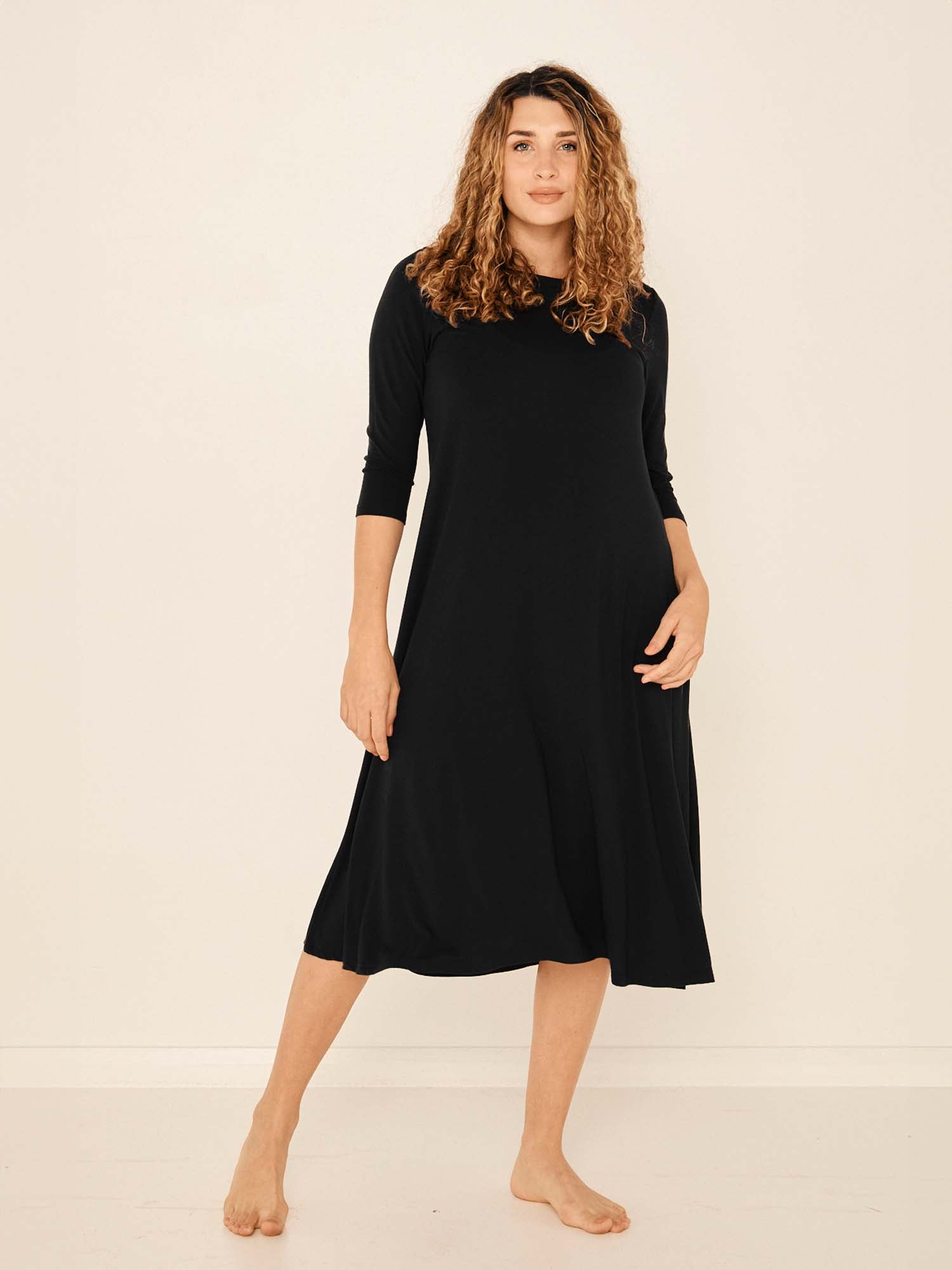 Model wearing a black mid sleeve 3/4 dress with a scoop neckline and generous swing in body, women's bamboo clothing