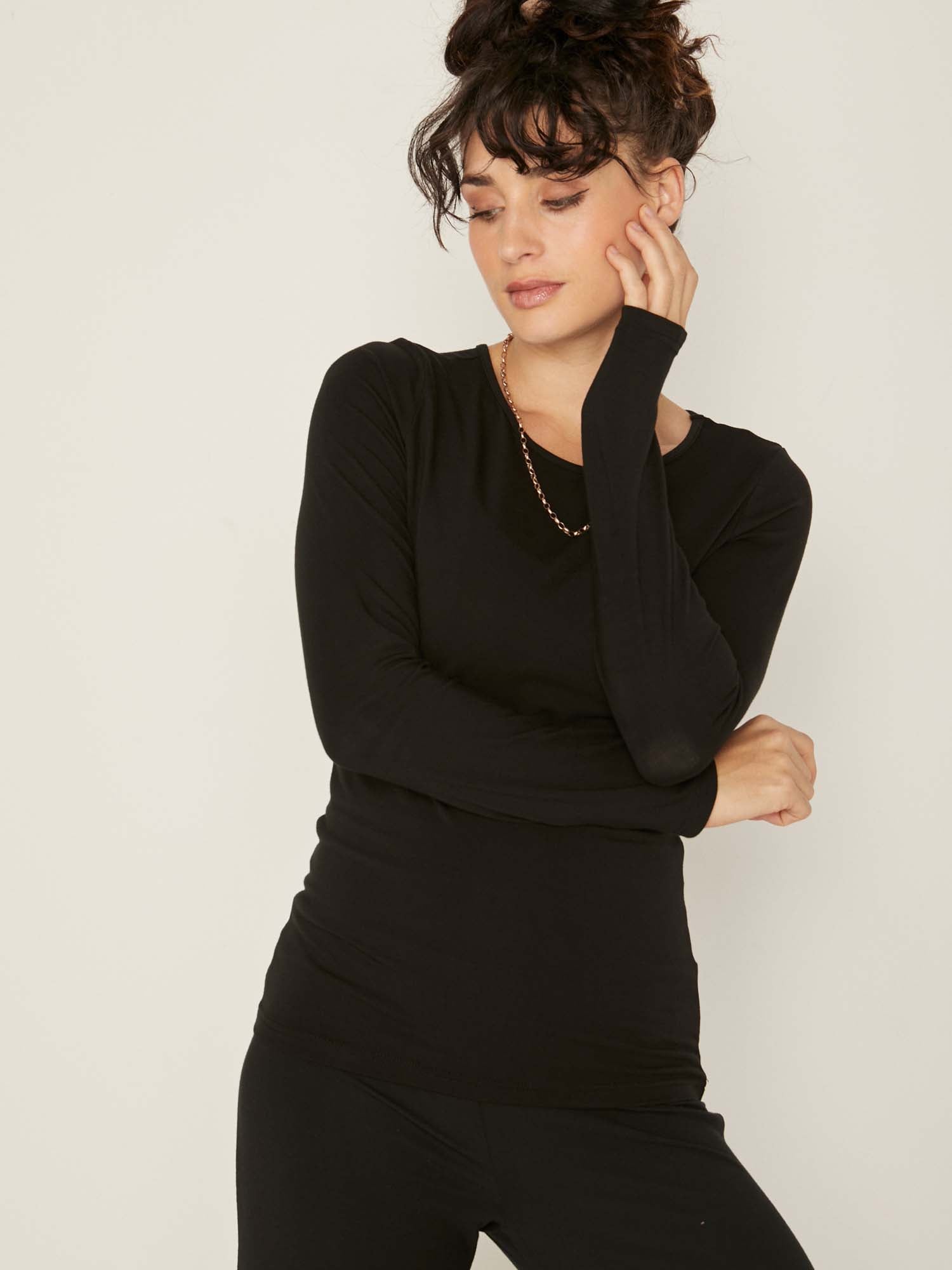 Model wearing a reversible black fitted body long sleeve t-shirt with crew and boat necklines, women's bamboo clothing