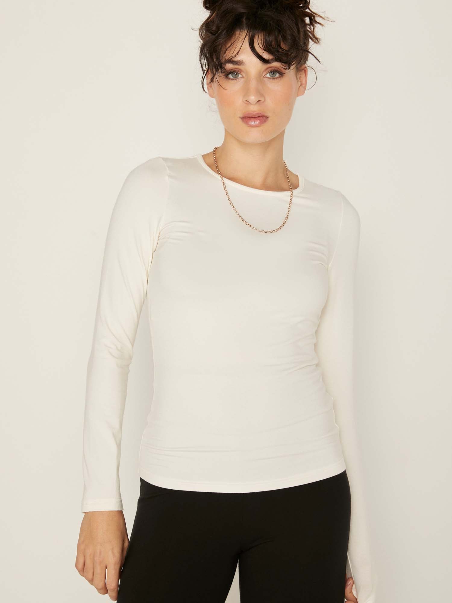 Model wearing a reversible cream fitted body long sleeve t-shirt with crew and boat necklines, women's bamboo clothing