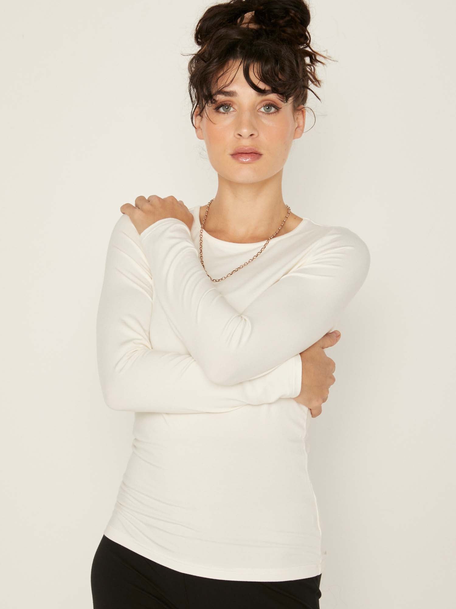 Model wearing a reversible cream fitted body long sleeve t-shirt with crew and boat necklines, women's bamboo clothing