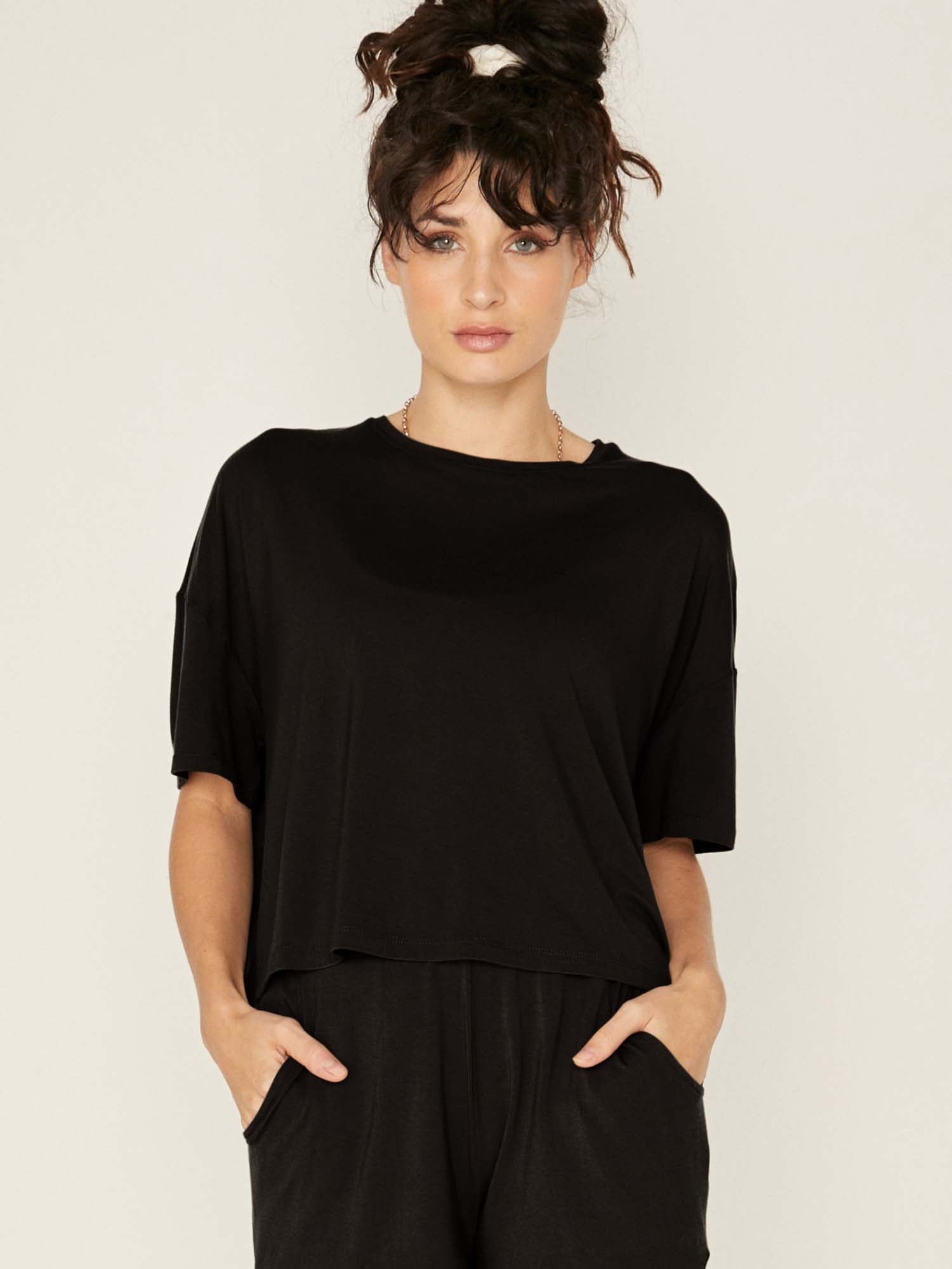 Model wearing a black cropped boxy t-shirt, crew neckline, relaxed short sleeve and drop shoulder, women's bamboo clothing