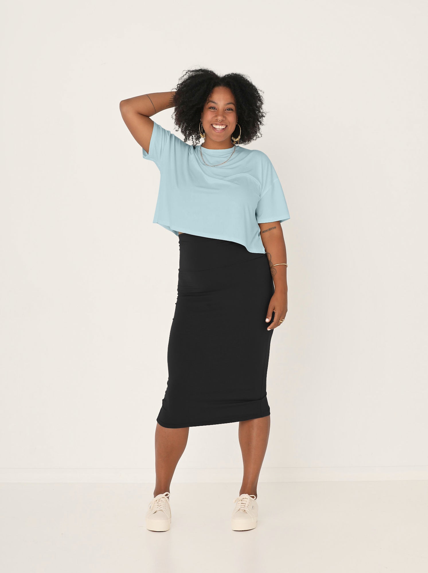 Woman wearing a light blue top and black skirt on a white background