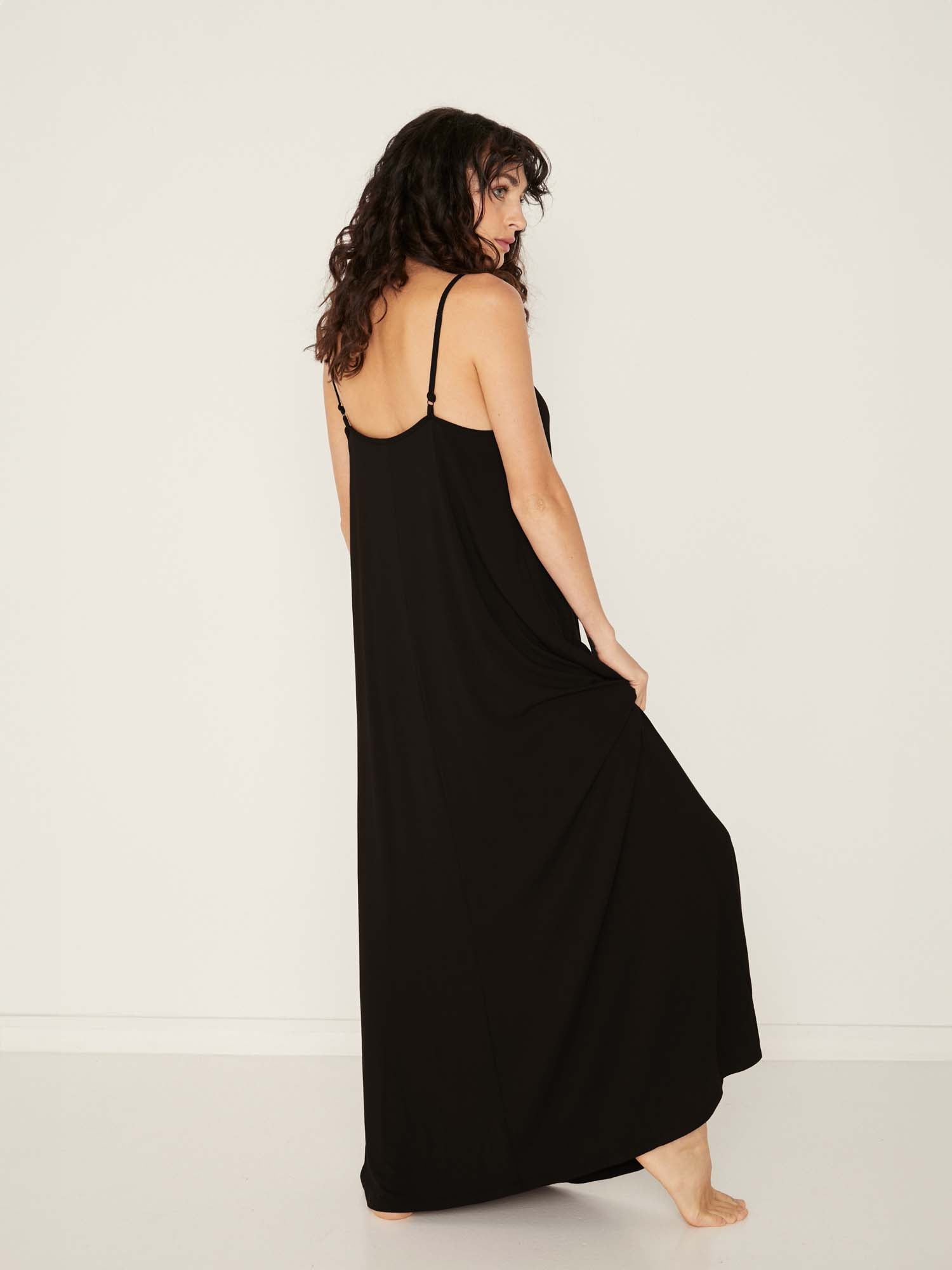 Model wearing a black swing maxi dress with a scoop neck and elasticated camisole straps, women's bamboo clothing