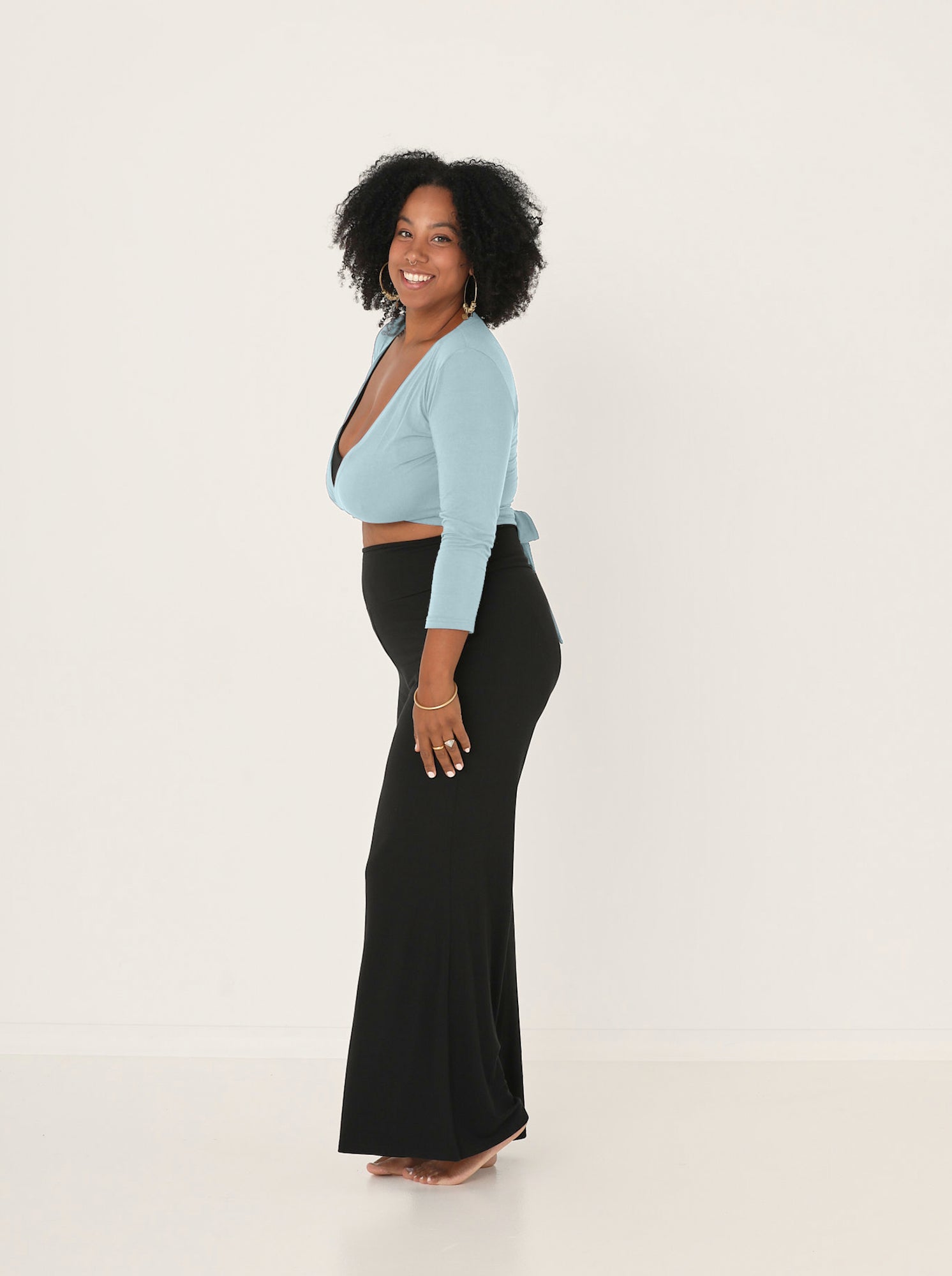 Woman wearing a light blue top and black pants on a white background