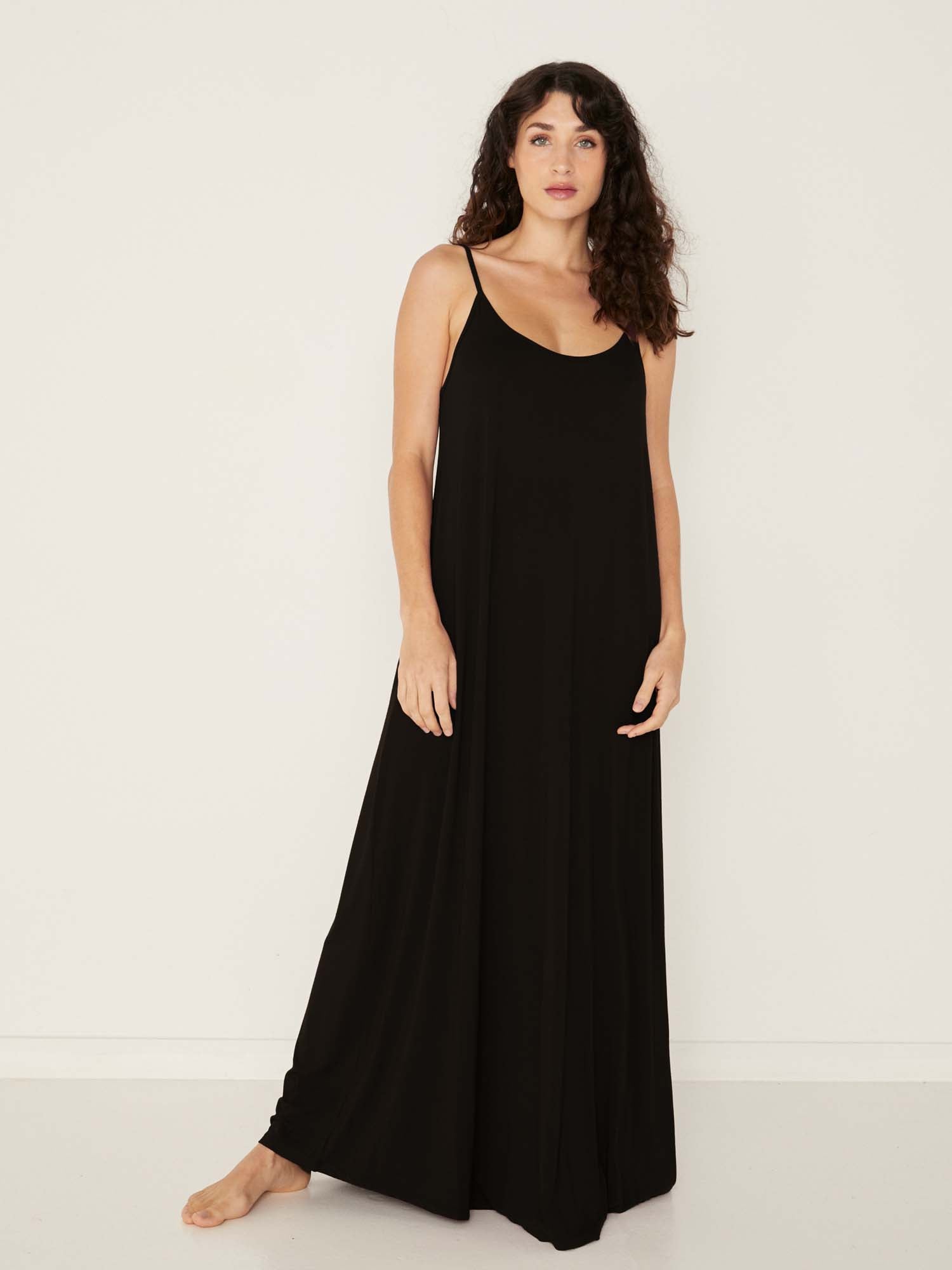 Model wearing a black swing maxi dress with a scoop neck and elasticated camisole straps, women's bamboo clothing