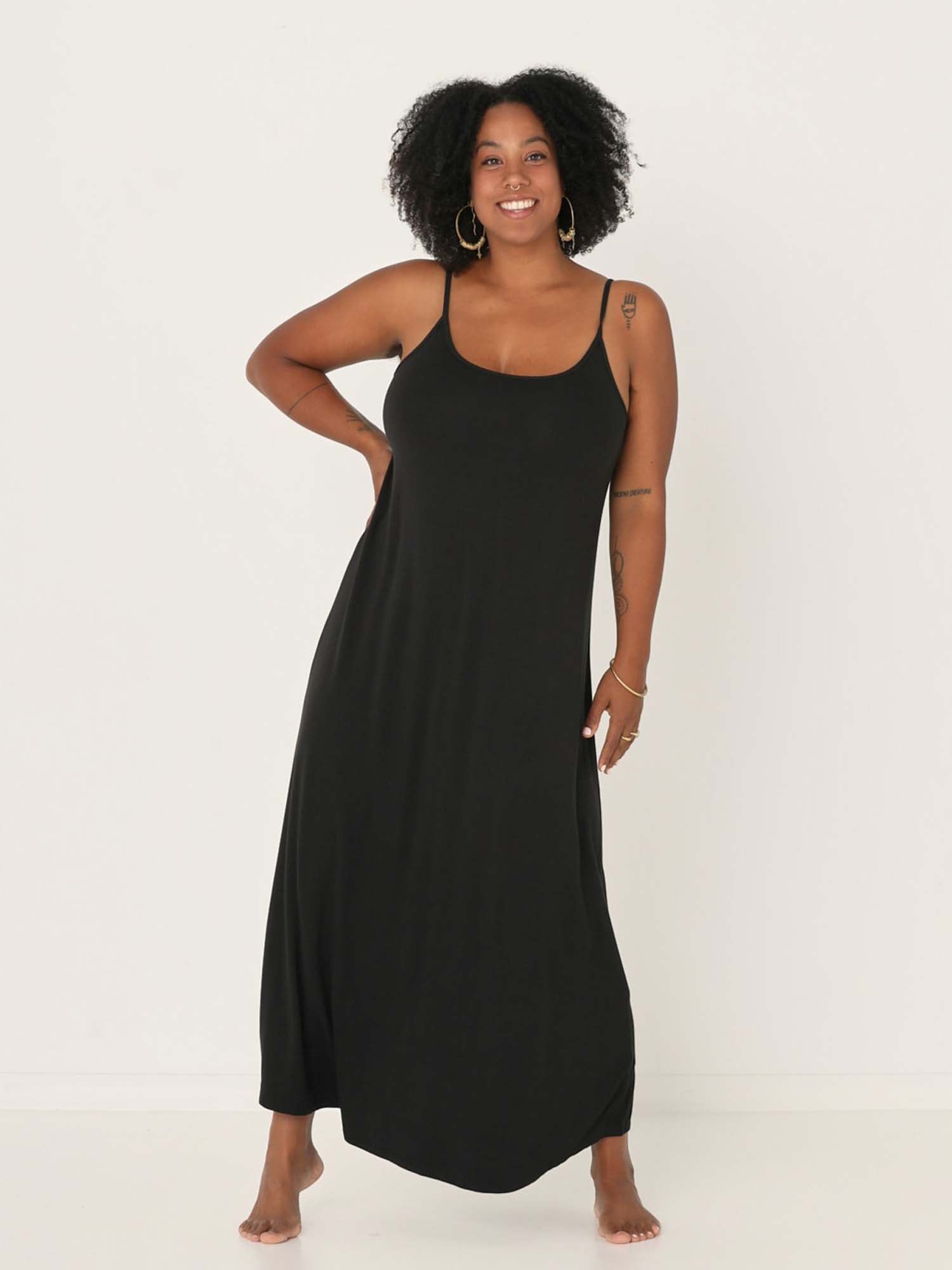 Model wearing a black swing maxi dress with a scoop neck and elasticated camisole straps, women's bamboo clothing