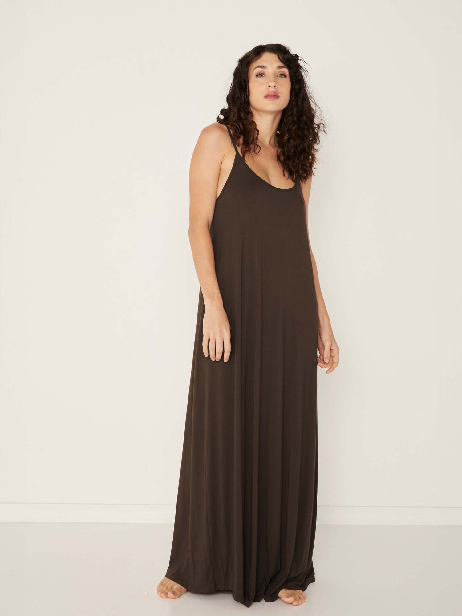 Model wearing a cocoa brown swing maxi dress with a scoop neck and elasticated camisole straps, women's bamboo clothing