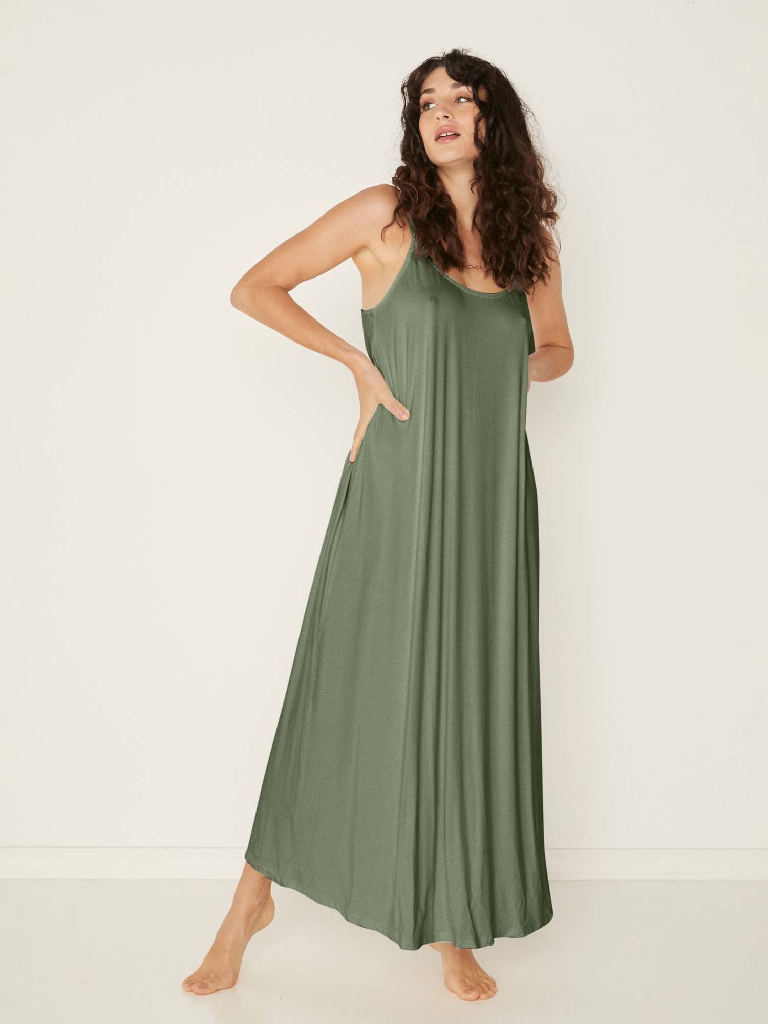Model wearing a eucalyptus green swing maxi dress with a scoop neck and elasticated camisole straps, women's bamboo clothing