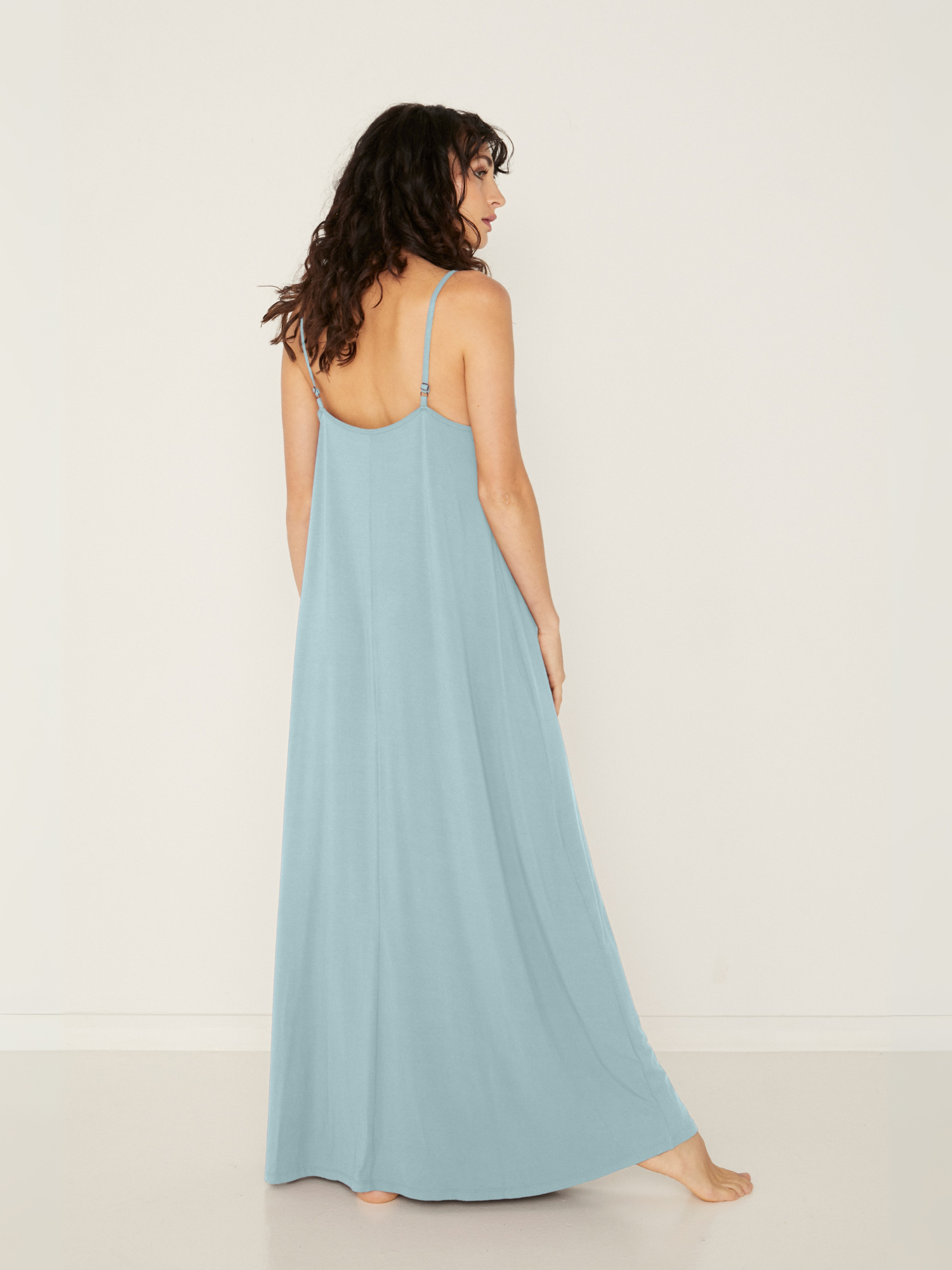 Woman wearing a light topaz blue bamboo maxi dress with thin straps against a white background