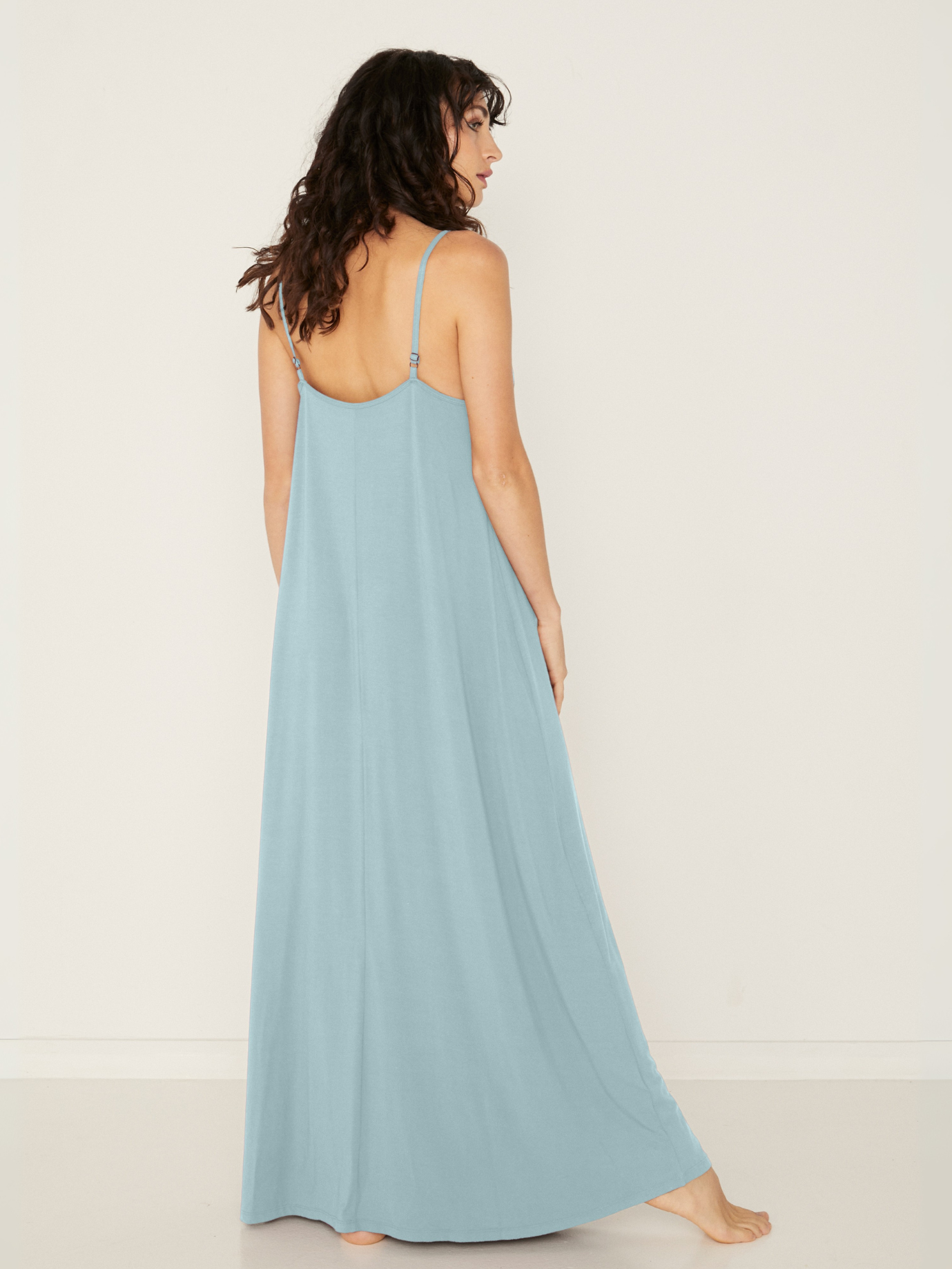 Woman wearing a light topaz blue bamboo maxi dress with thin straps against a white background