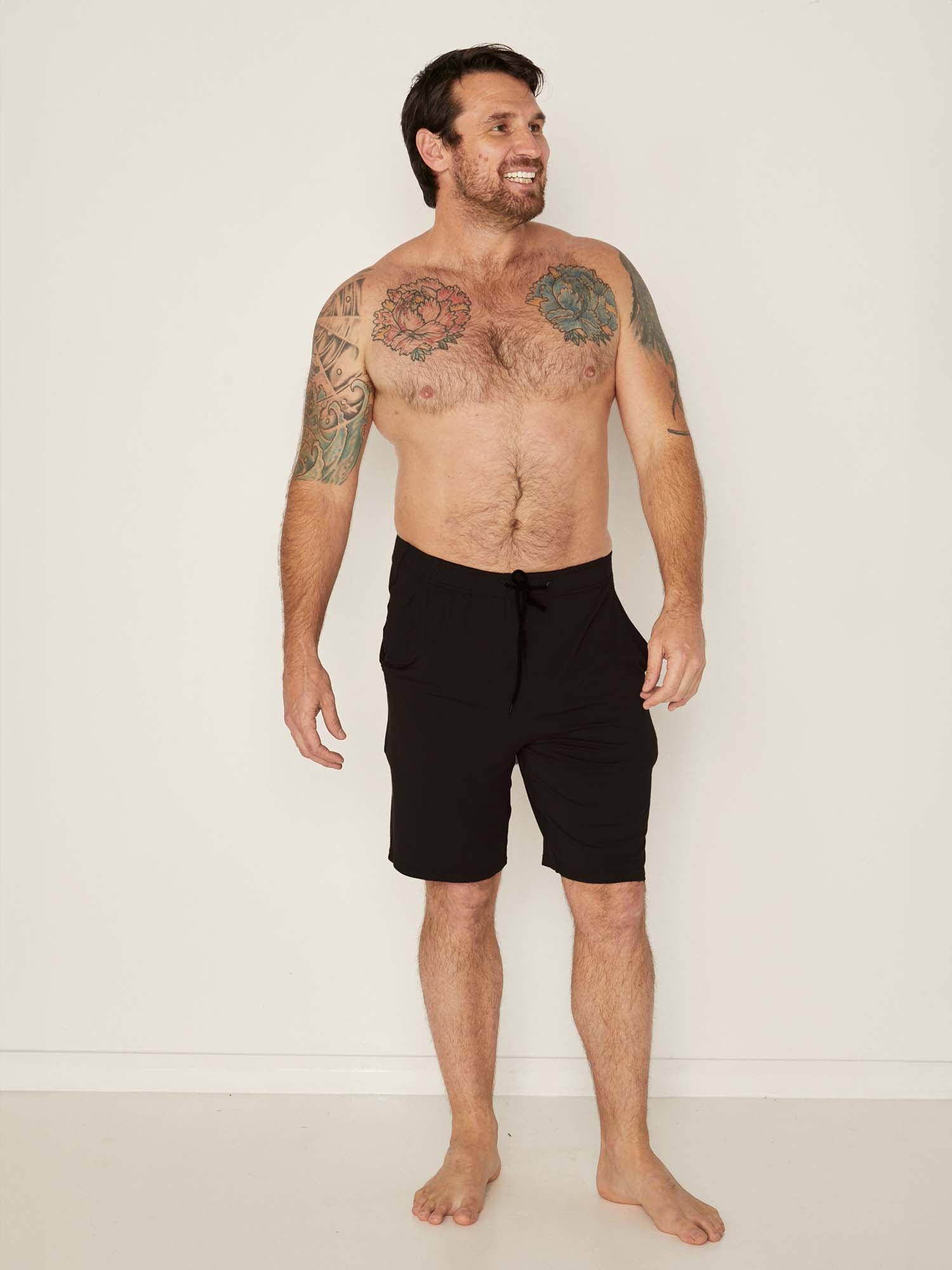Male model wearing knee length black casual shorts with elasticised waist and deep pockets, men's bamboo clothing