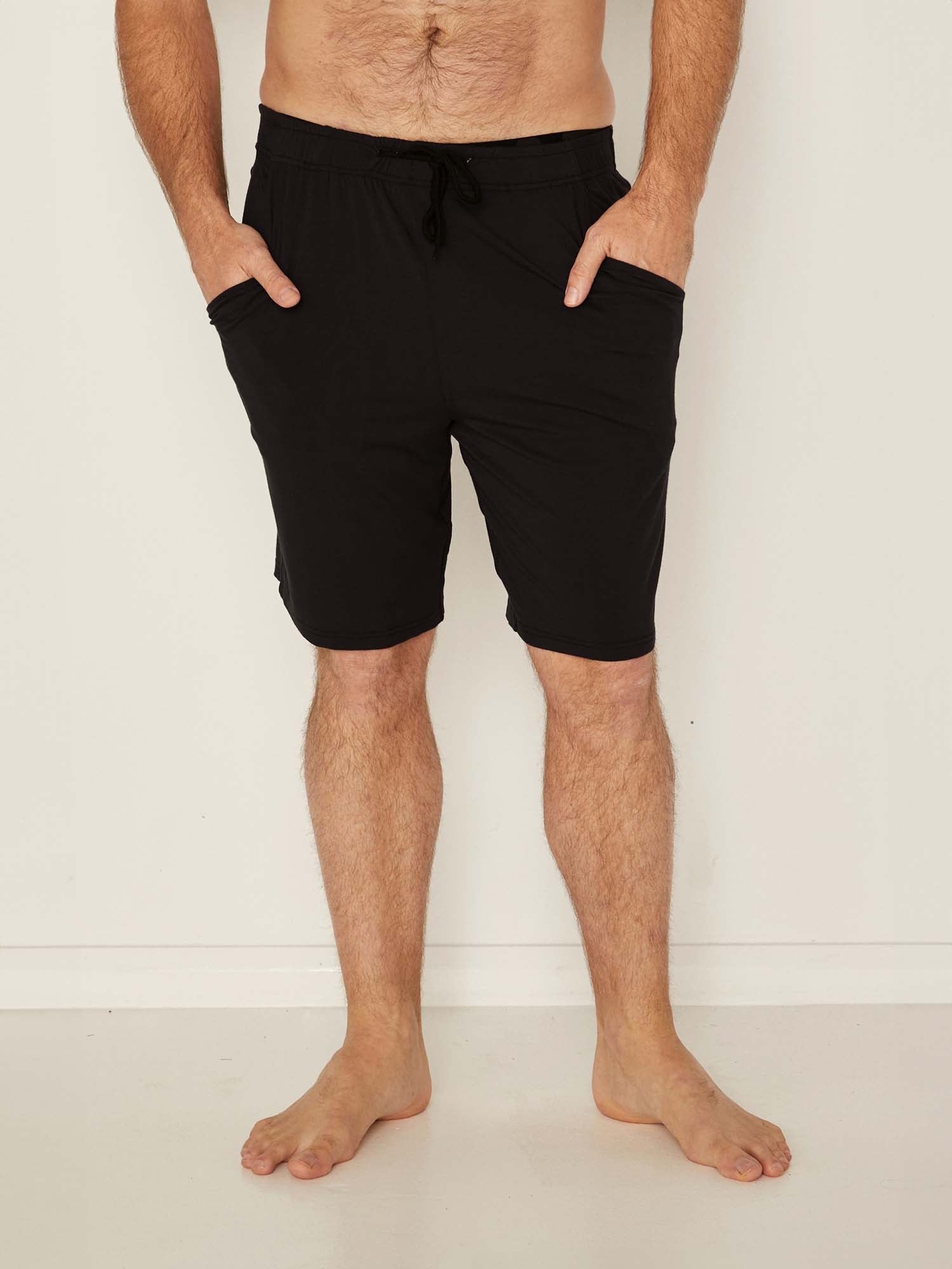 Male model wearing knee length black casual shorts with elasticised waist and deep pockets, men's bamboo clothing