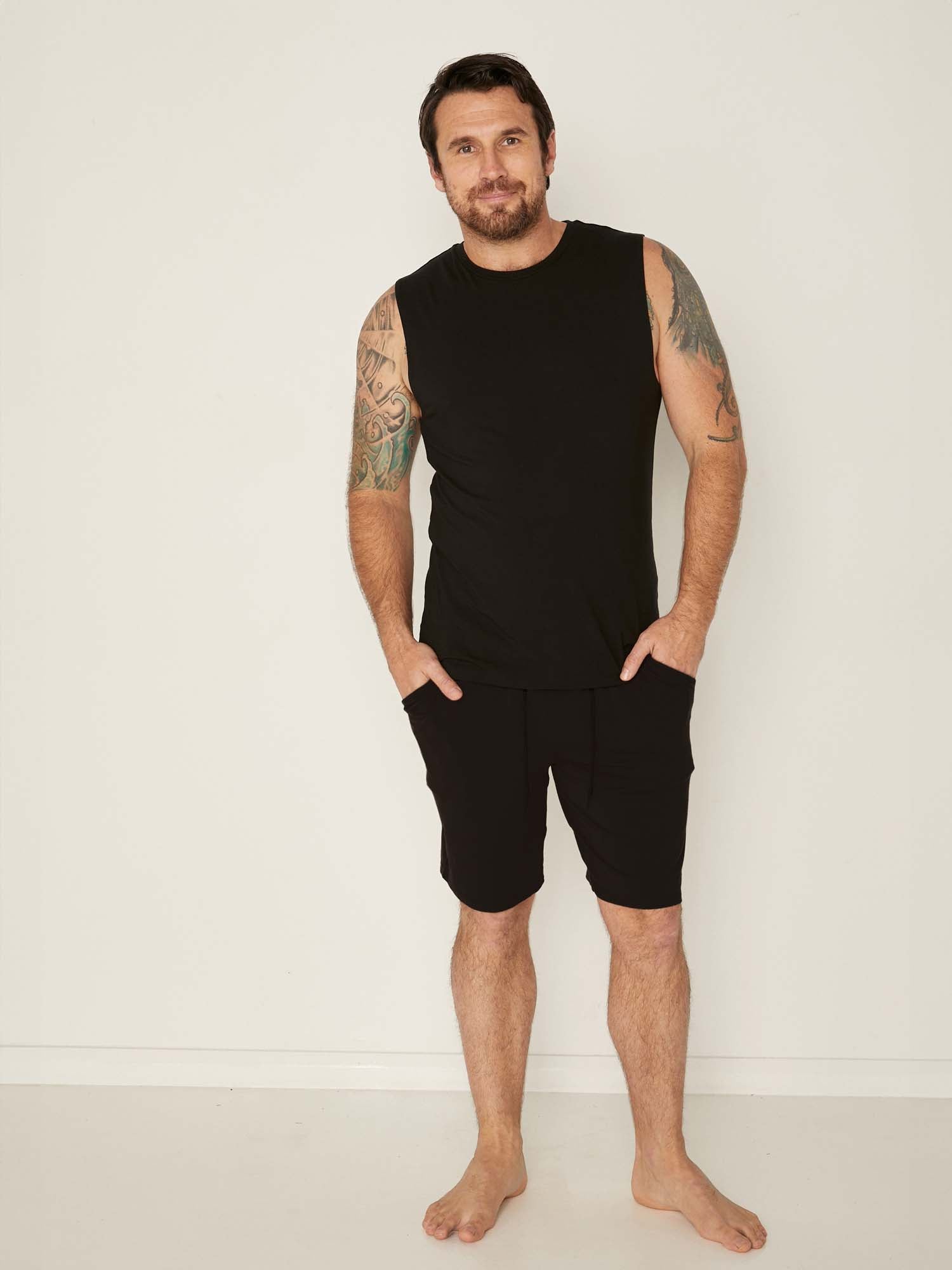 Male model wearing knee length black casual shorts with elasticised waist and deep pockets, men's bamboo clothing