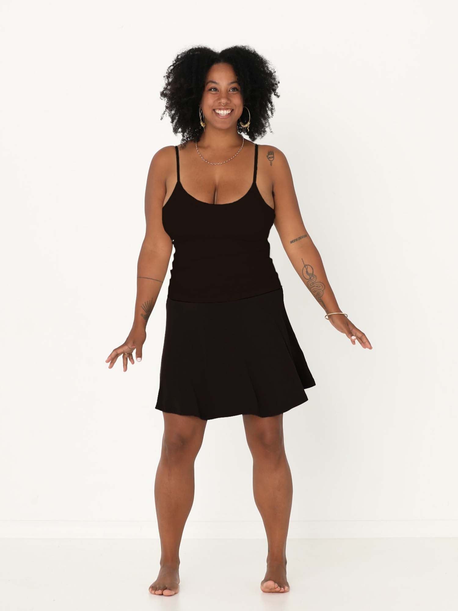 Model wearing black knee length swing style swishy mini skirt with adjustable high waistband, women's bamboo clothing