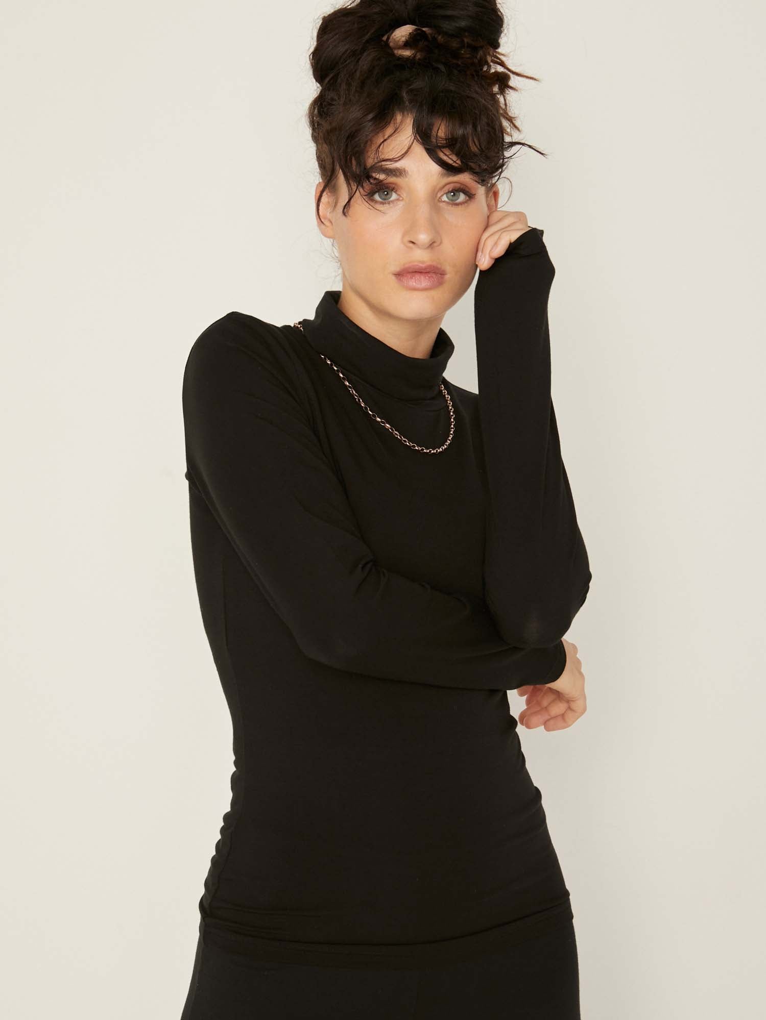 Model wearing black high roll neck fitted skivvy, fitted long sleeves, women's bamboo clothing