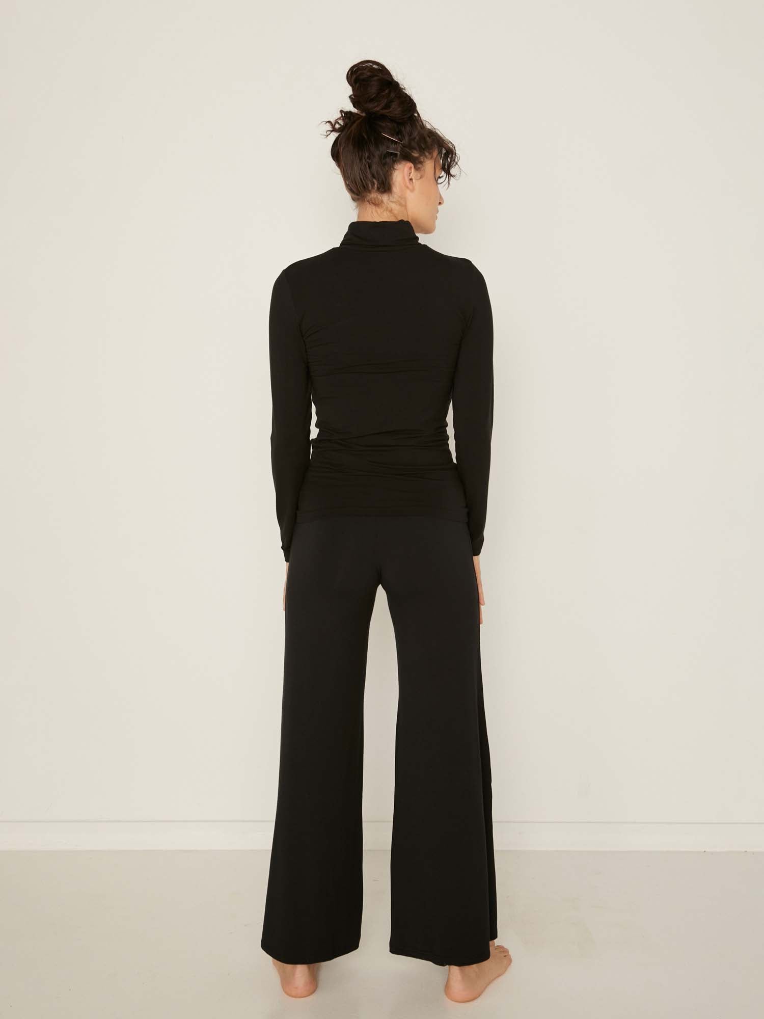 Model wearing black high roll neck fitted skivvy, fitted long sleeves, women's bamboo clothing