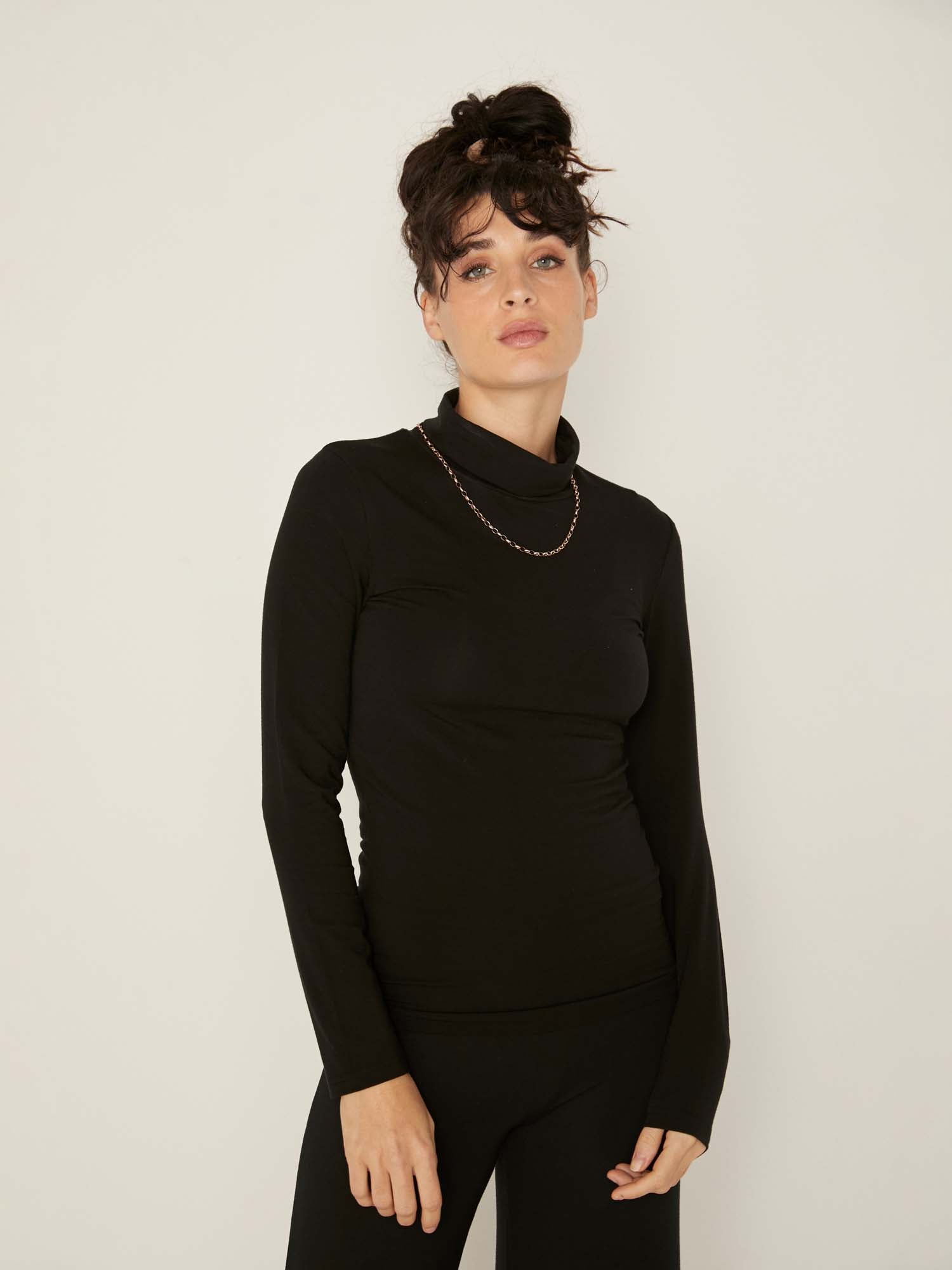 Model wearing black high roll neck fitted skivvy, fitted long sleeves, women's bamboo clothing