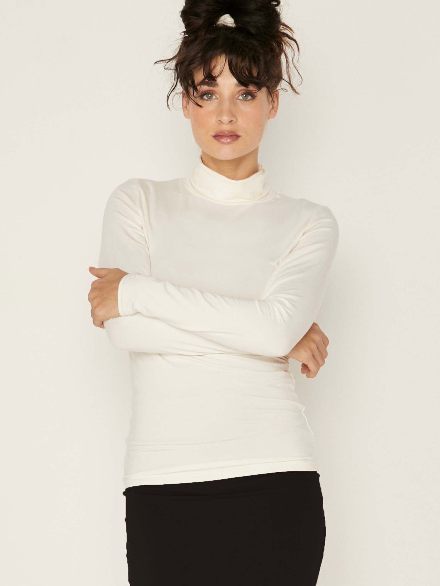 Model wearing cream high roll neck fitted skivvy, fitted long sleeves, women's bamboo clothing