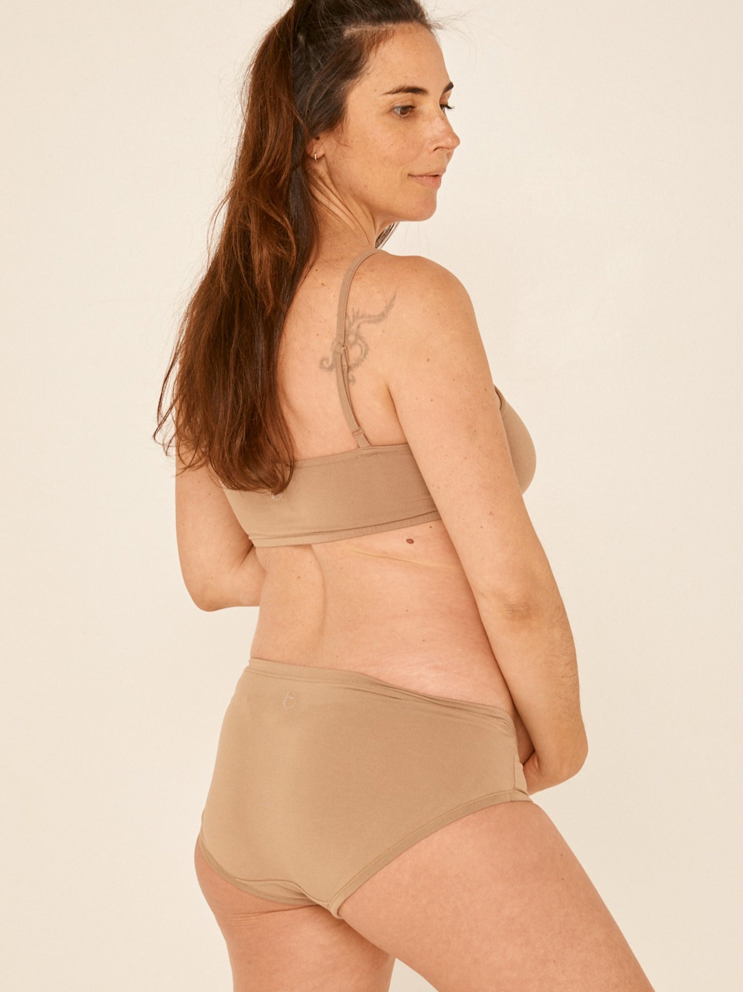 Model wearing a caramel brown full brief with mid waist and soft leg banding to lift and shape bottom, women's bamboo underwear