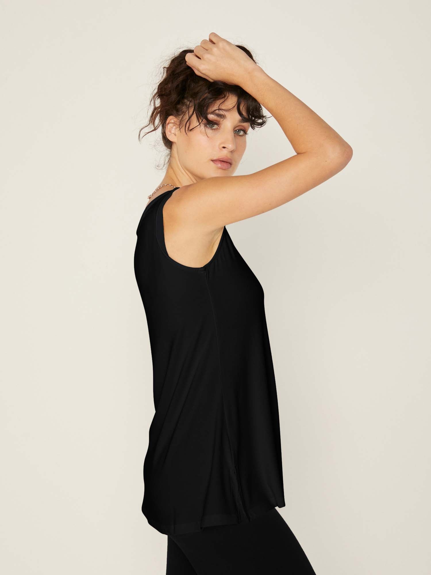 Model wearing a reversible black a-line singlet with scoop and boat necklines and long line body, women's bamboo clothing