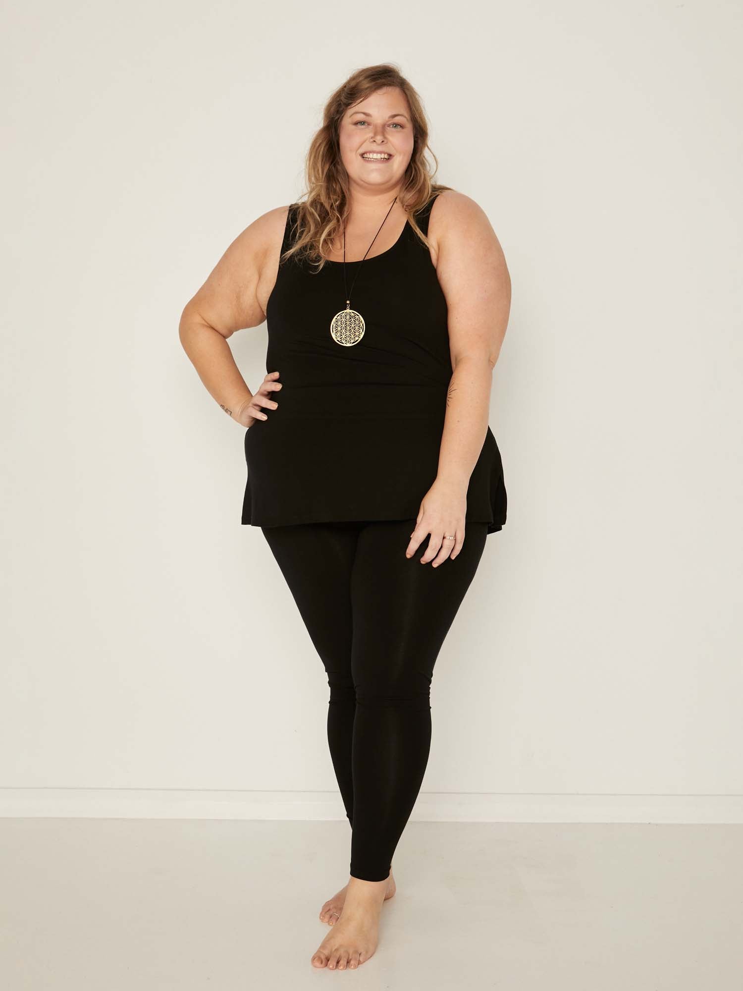 Model wearing a reversible black a-line singlet with scoop and boat necklines and long line body, women's bamboo clothing
