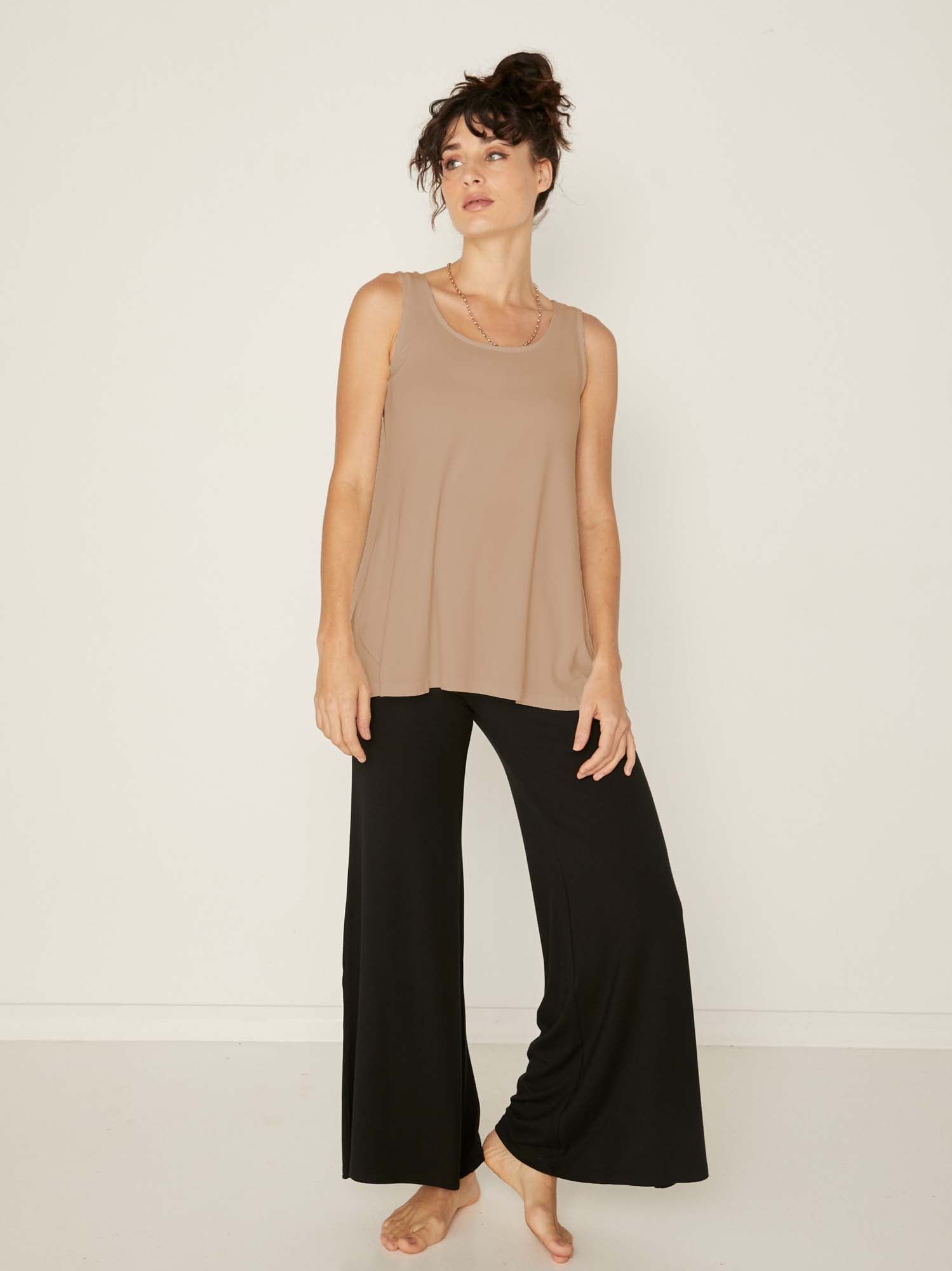Model wearing a reversible caramel a-line singlet with scoop and boat necklines and long line body, women's bamboo clothing
