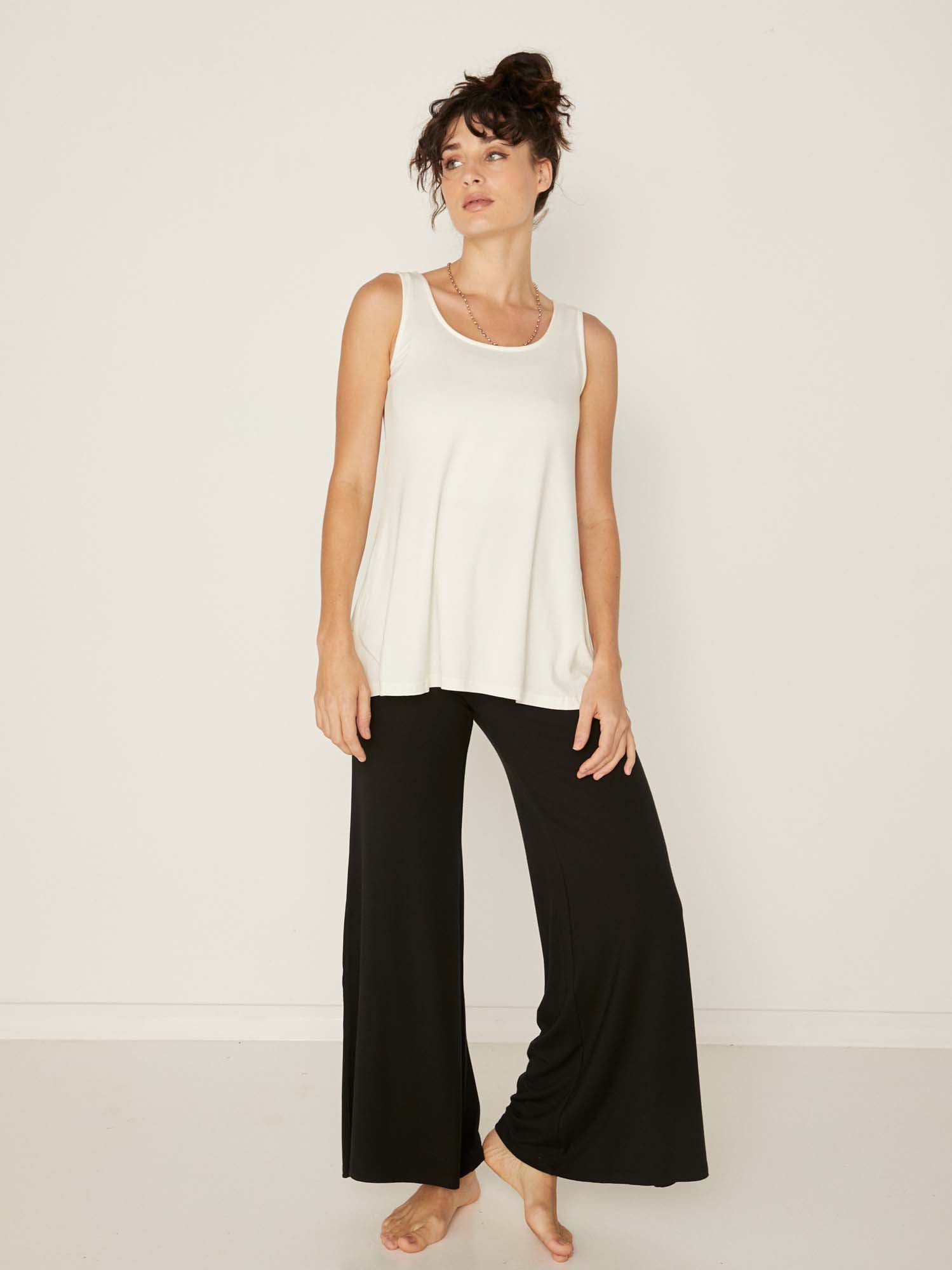 Model wearing a reversible cream a-line singlet with scoop and boat necklines and long line body, women's bamboo clothing