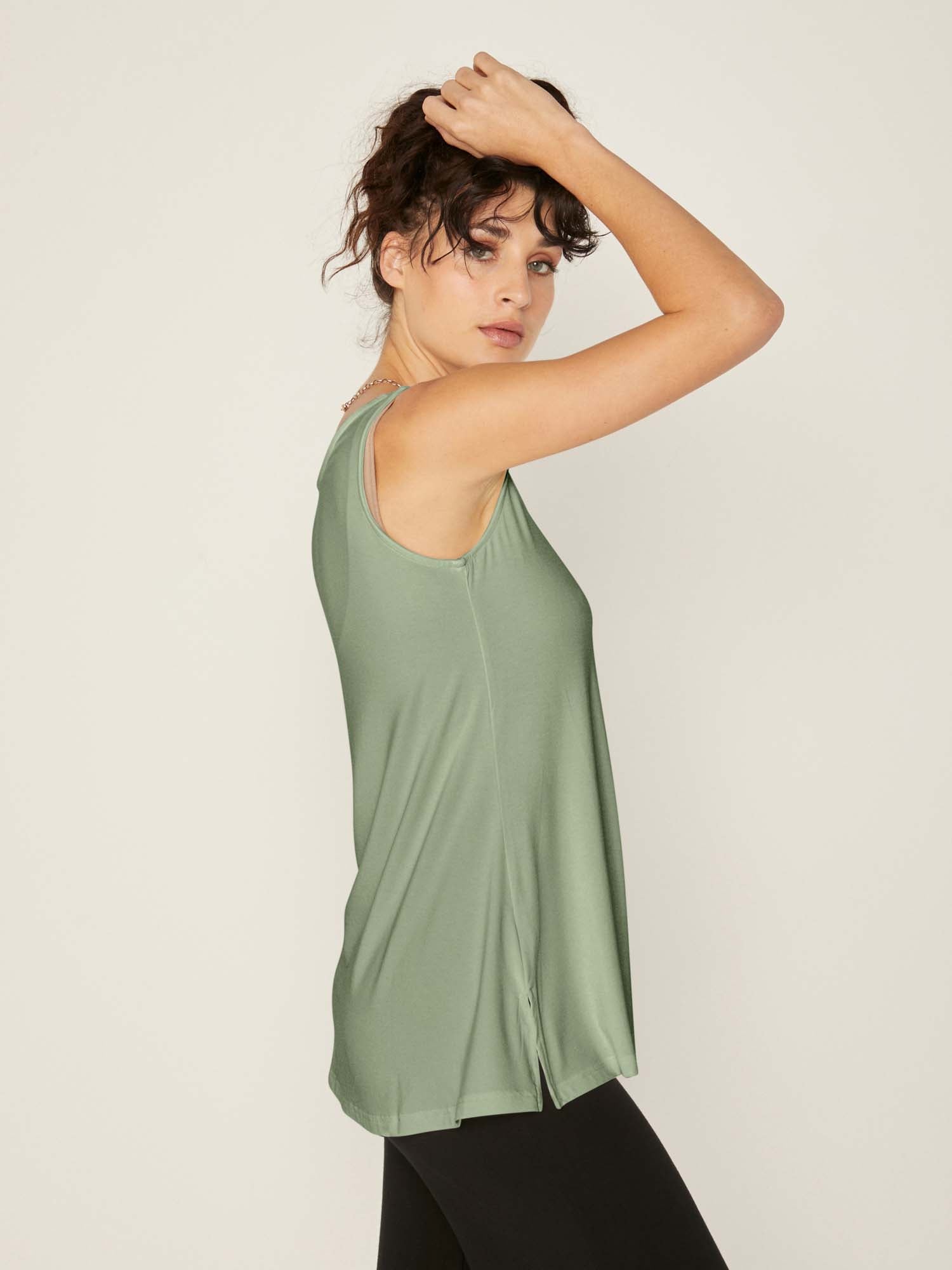Model wearing a reversible eucalyptus green a-line singlet with scoop and boat necklines and long line body, women's bamboo clothing