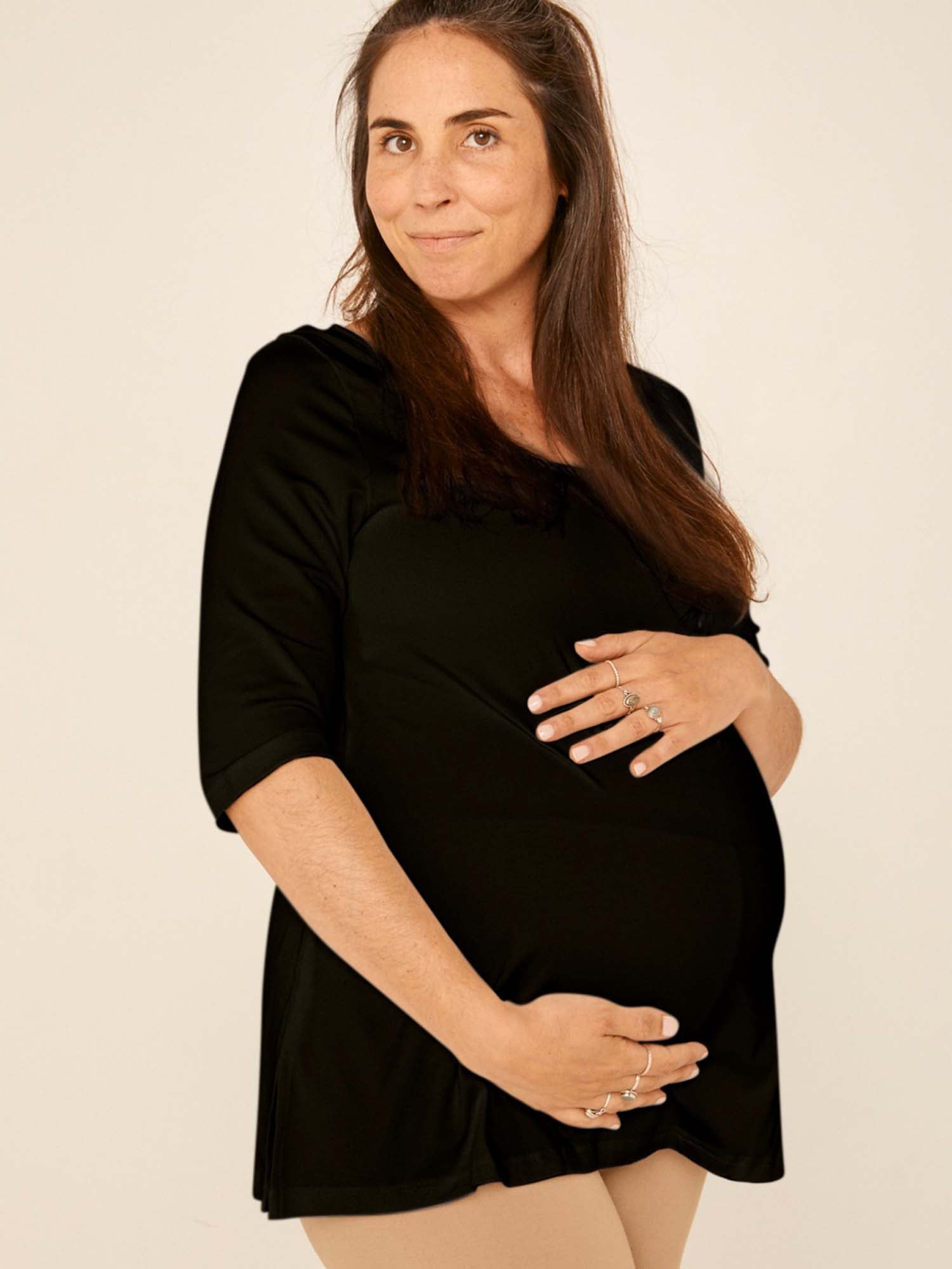 Model wearing a reversible black mid sleeve t-shirt with scoop and boat necklines, a-line long line body, women's bamboo clothing
