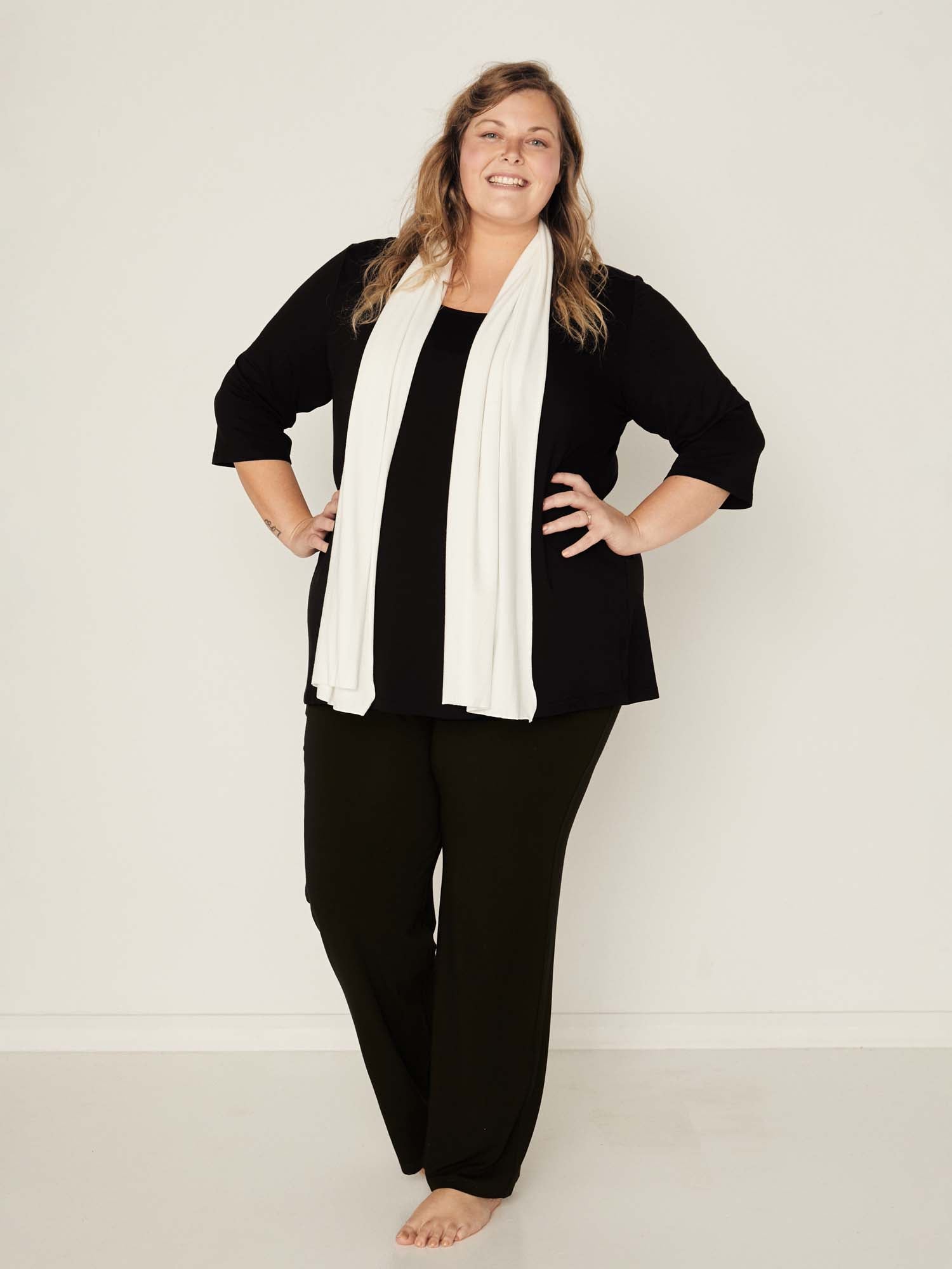 Model wearing a reversible black mid sleeve t-shirt with scoop and boat necklines, a-line long line body, women's bamboo clothing