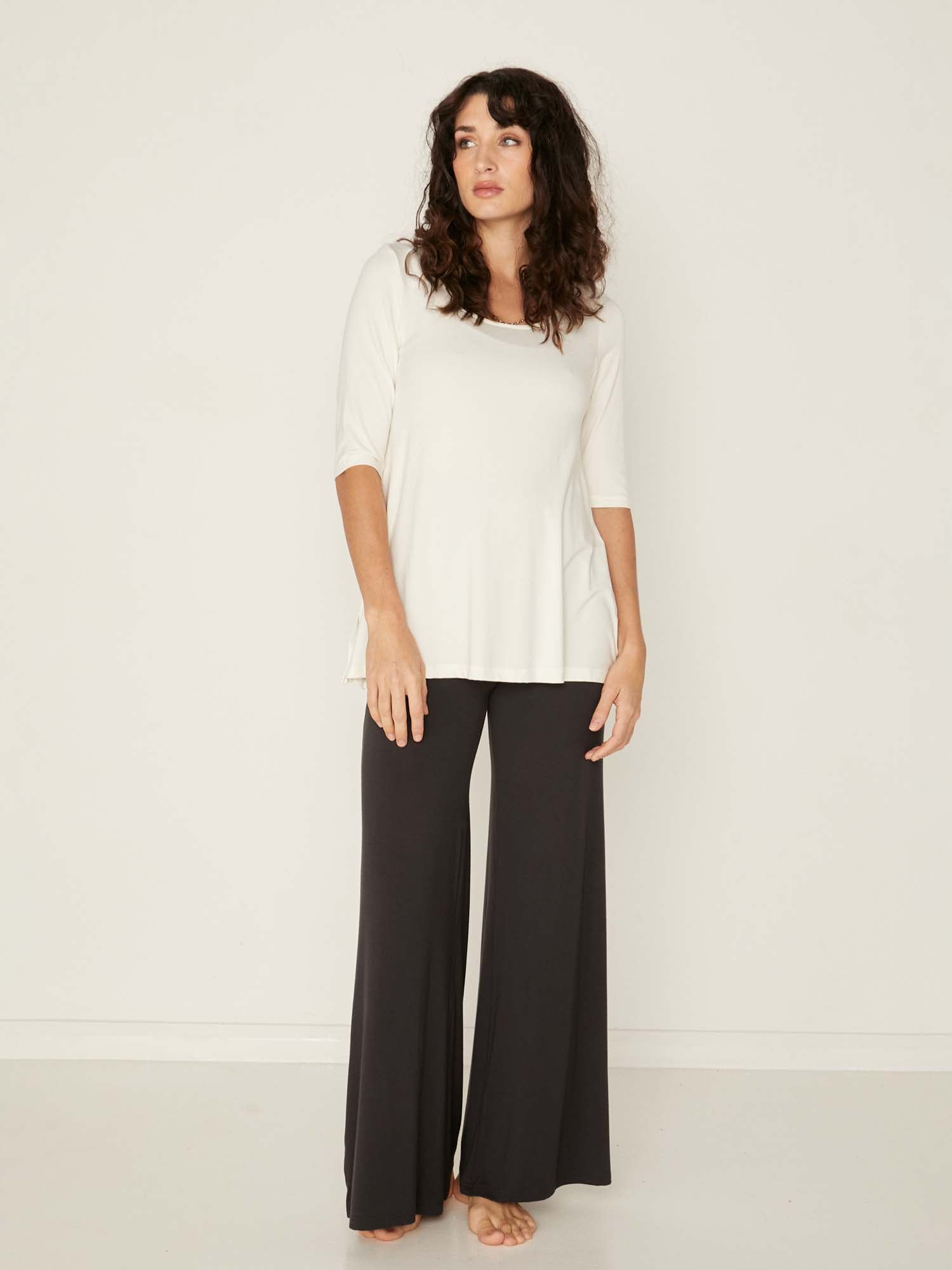 Model wearing a reversible cream mid sleeve t-shirt with scoop and boat necklines, a-line long line body, women's bamboo clothing