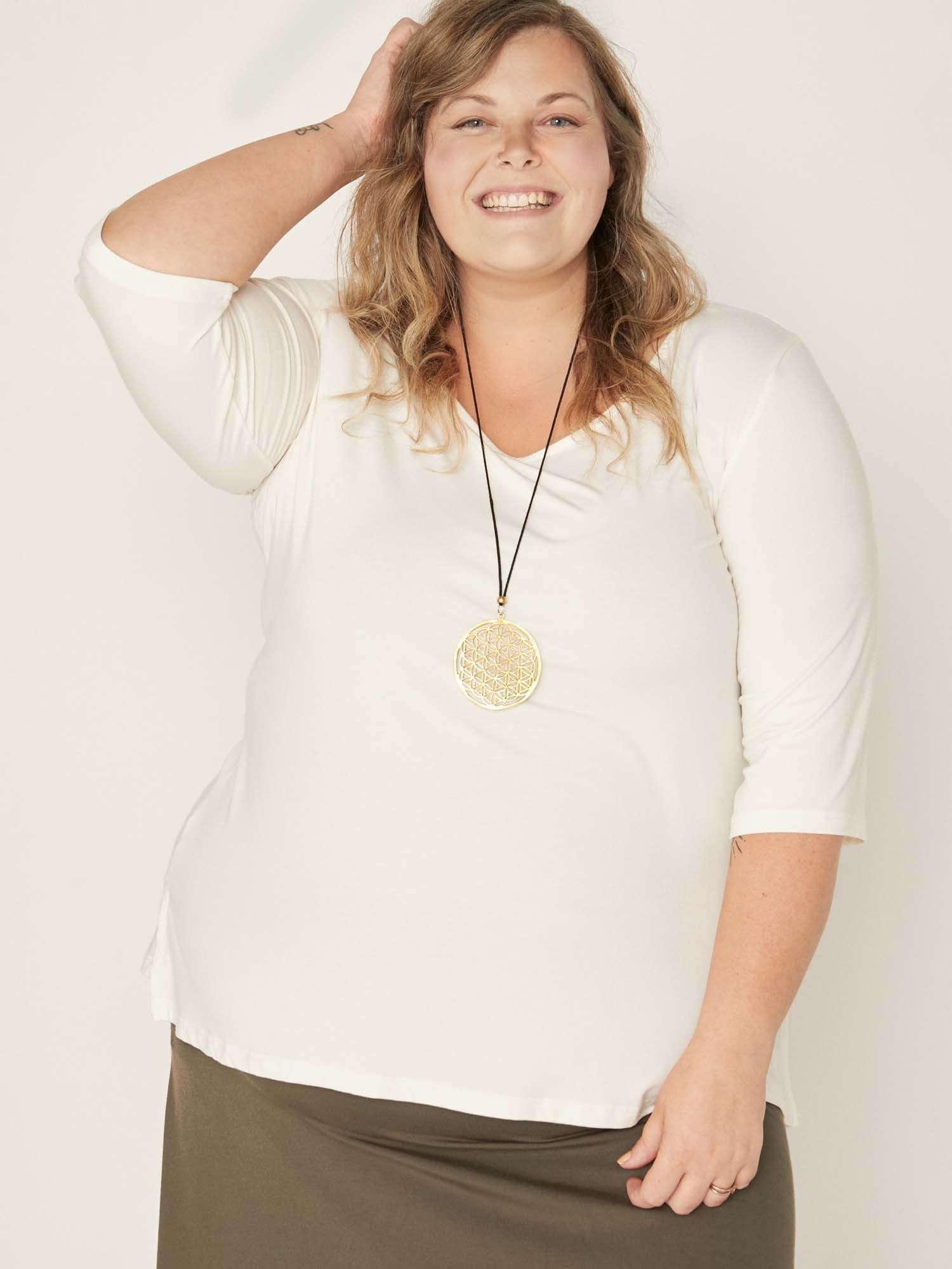 Model wearing a reversible cream mid sleeve t-shirt with scoop and boat necklines, a-line long line body, women's bamboo clothing