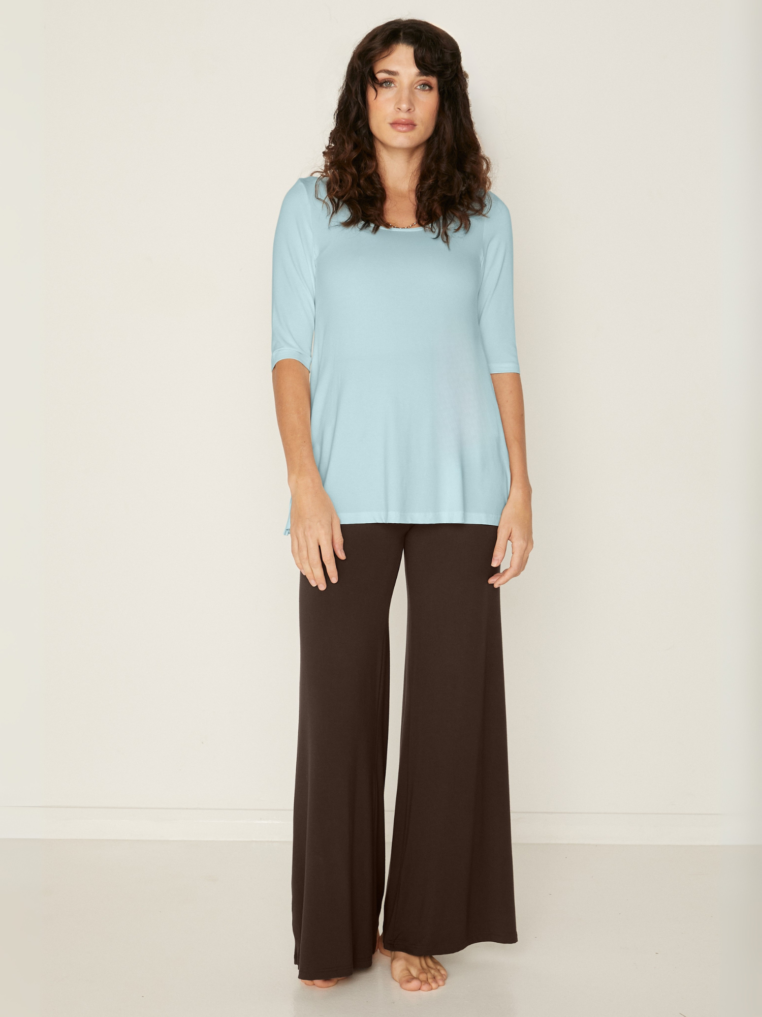 Woman wearing a bamboo light topaz blue mid sleeve t-shirt with a scoop neckline and cocoa brown wide leg palazzo pants on a white background