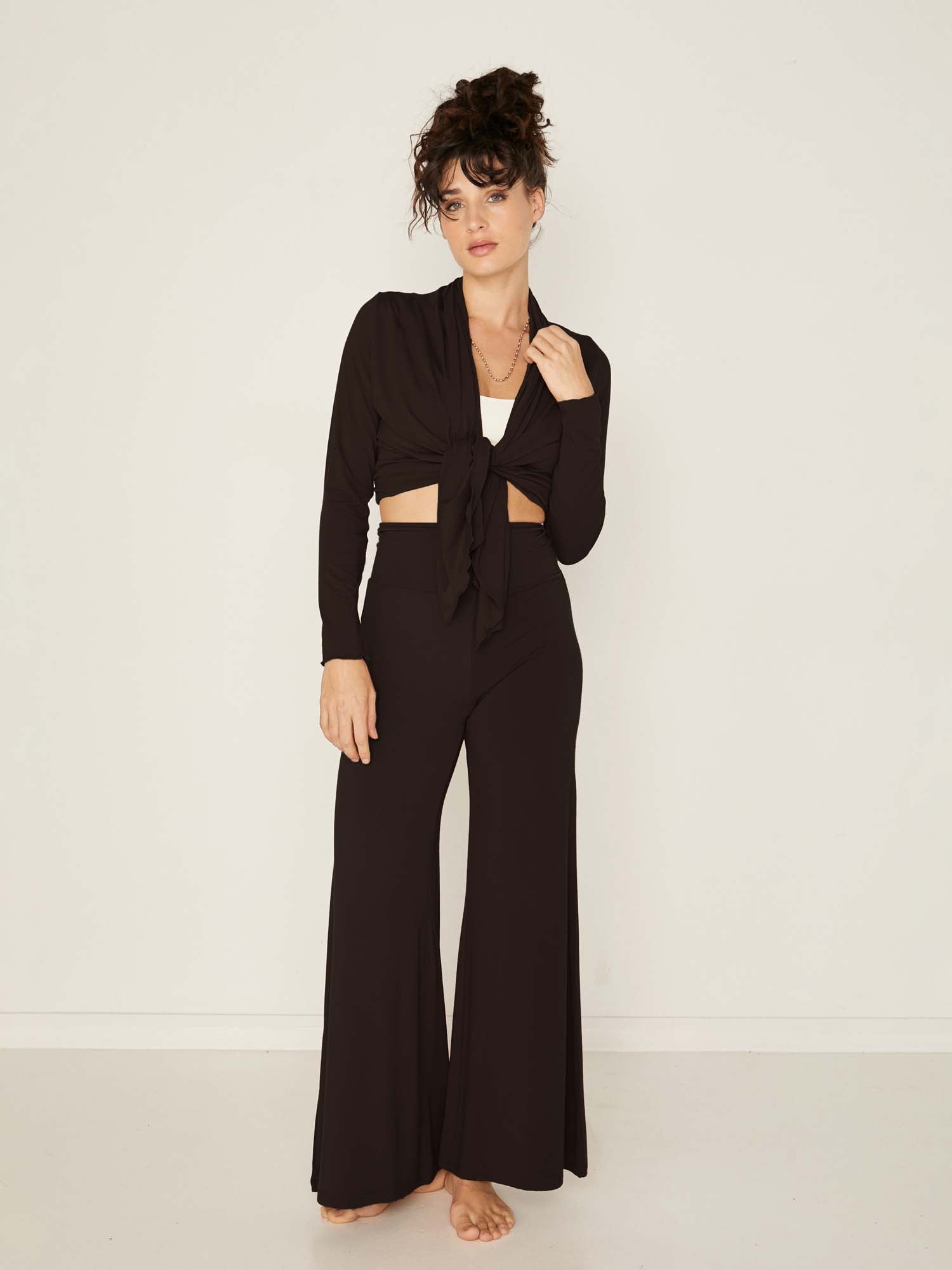 Model wearing convertible black mid cardigan, worn tied at front or worn open with long fitted sleeves, women's bamboo clothing