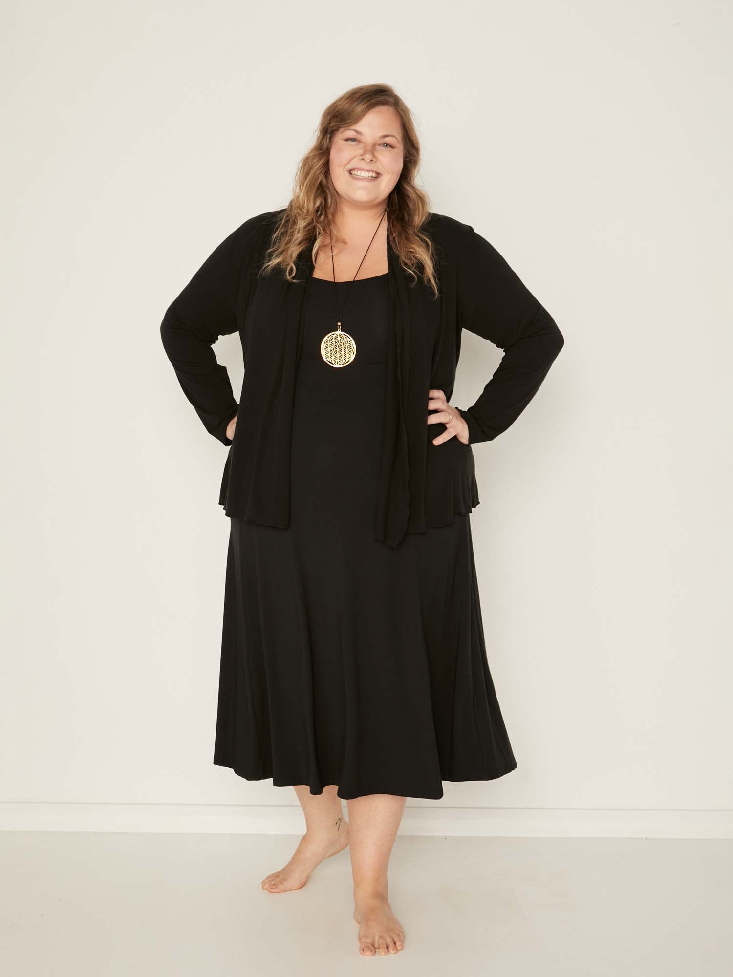 Model wearing convertible black mid cardigan, worn tied at front or worn open with long fitted sleeves, women's bamboo clothing