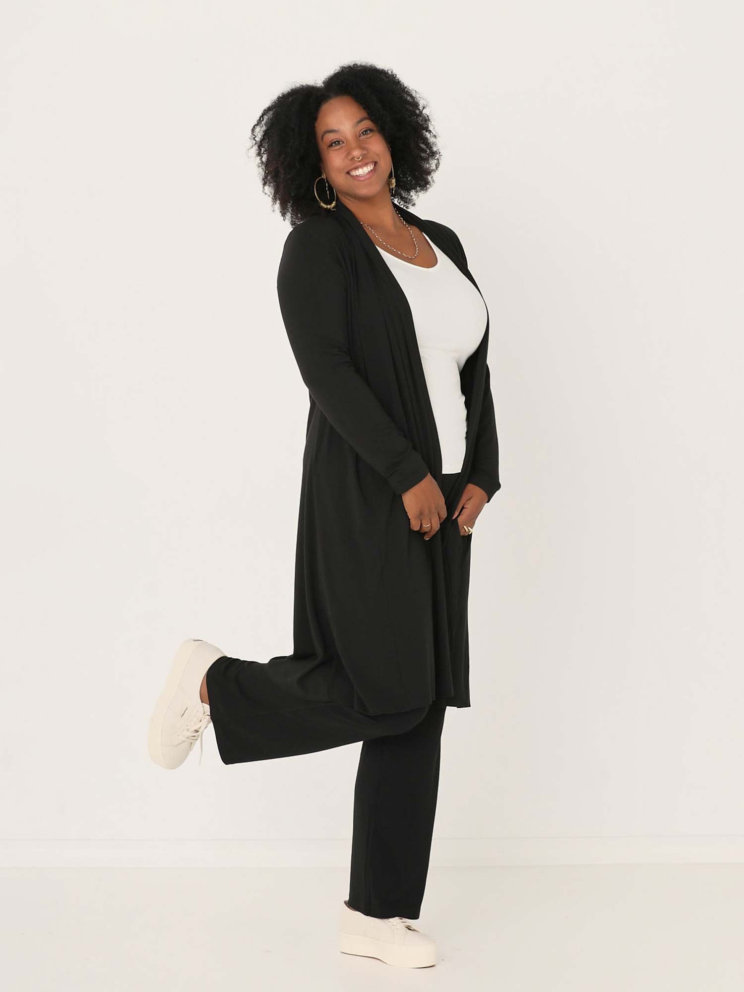 Model wearing black long cardigan, below knee length jacket with long fitted sleeves, women's bamboo clothing
