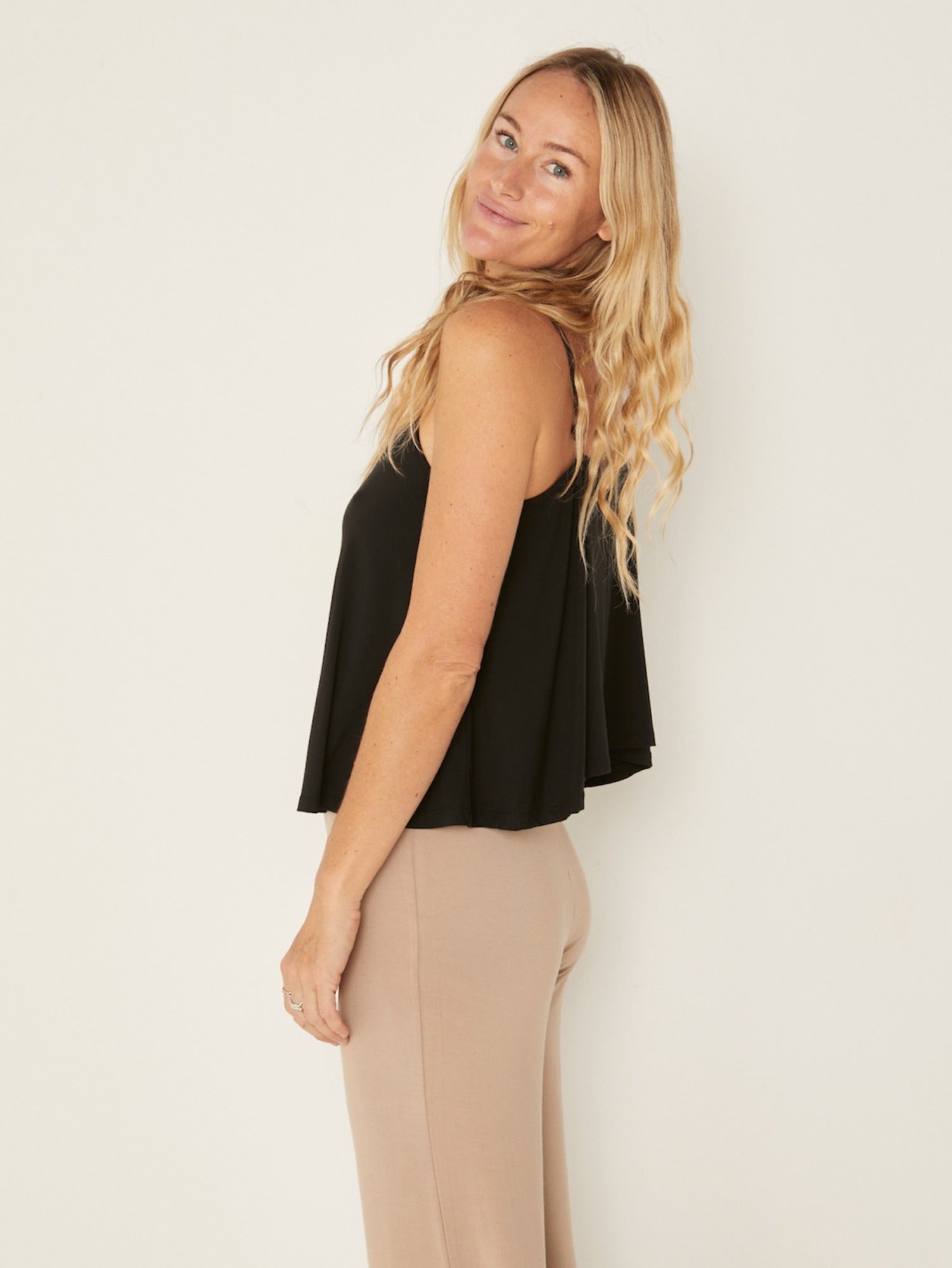 Model wearing a black swing style singlet with a scoop neck and elasticated camisole straps, women's bamboo clothing
