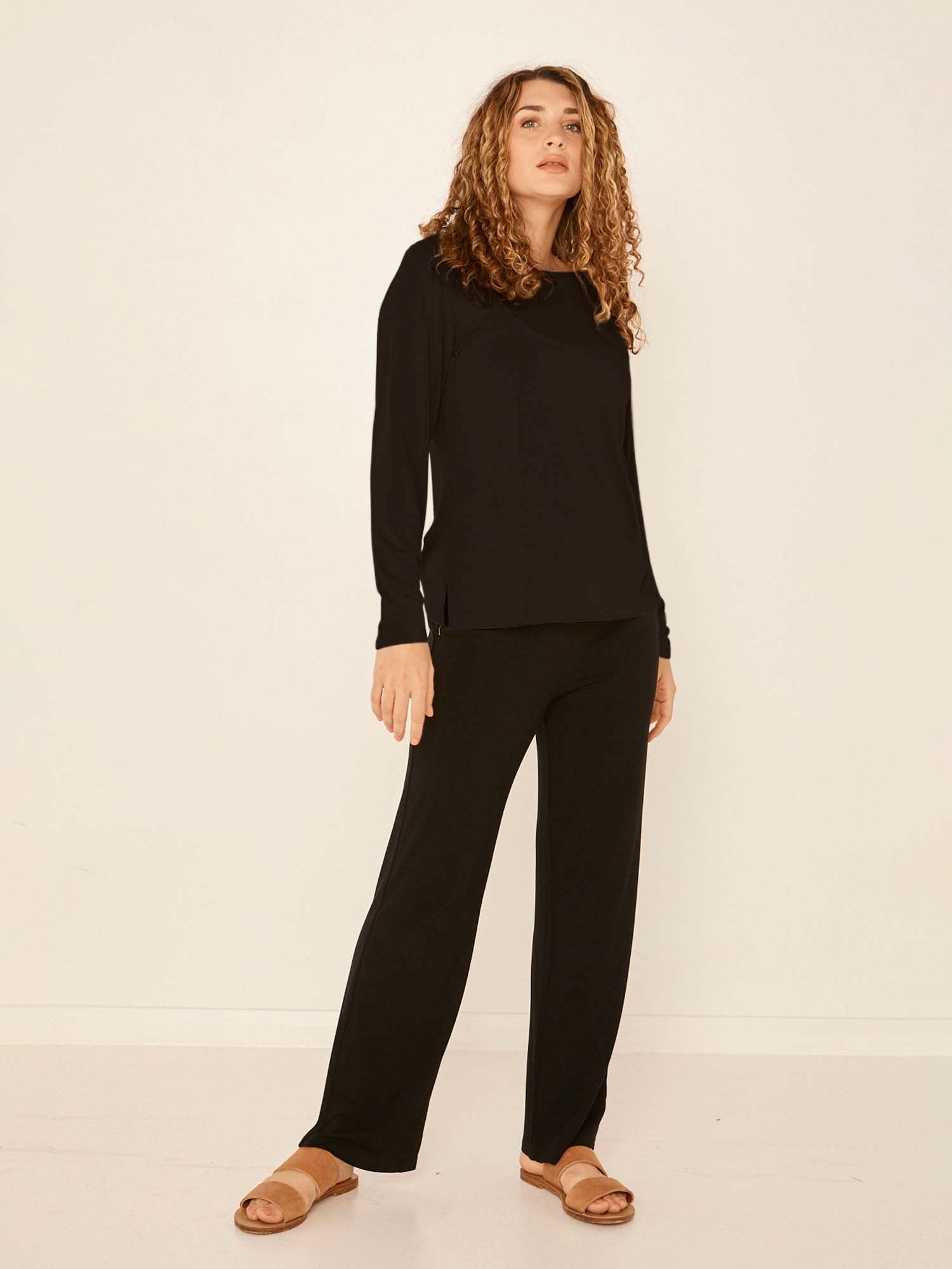Model wearing a black boat neck long sleeve t-shirt, fitted through shoulders and chest with loose fit to waist, women's bamboo clothing
