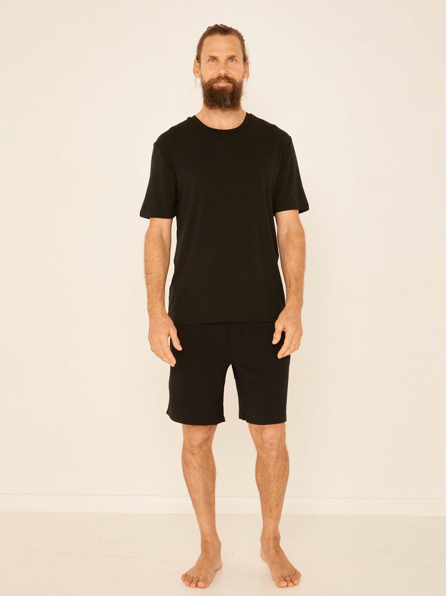Male model wearing black casual shorts, above knee length with fly front detailing, pockets and elasticised waistband, men's bamboo clothing